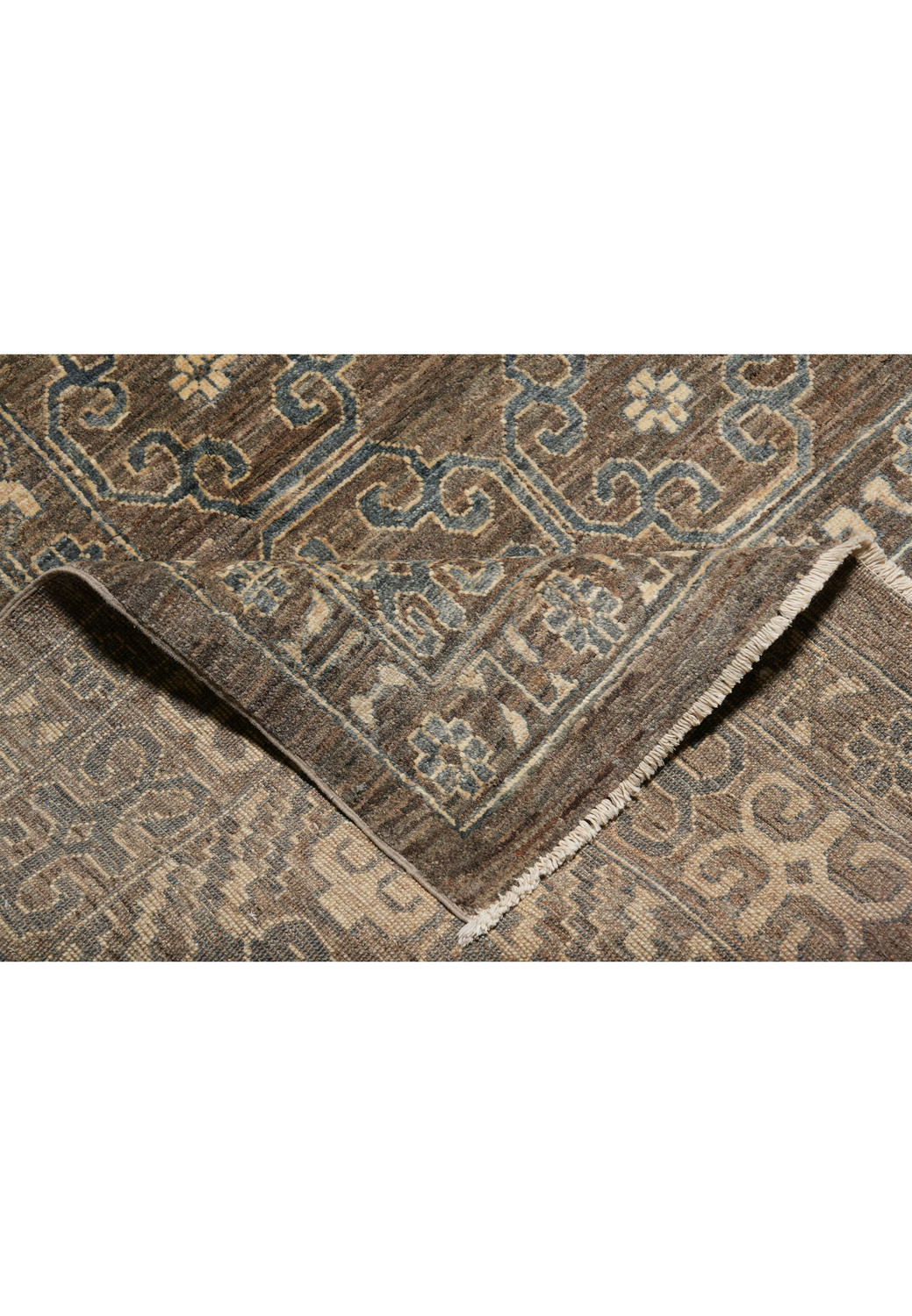 Close-up of Zigler rug wool pile, earthy brown-grey tones with subtle beige and faded blue highlights, hand-knotted texture.