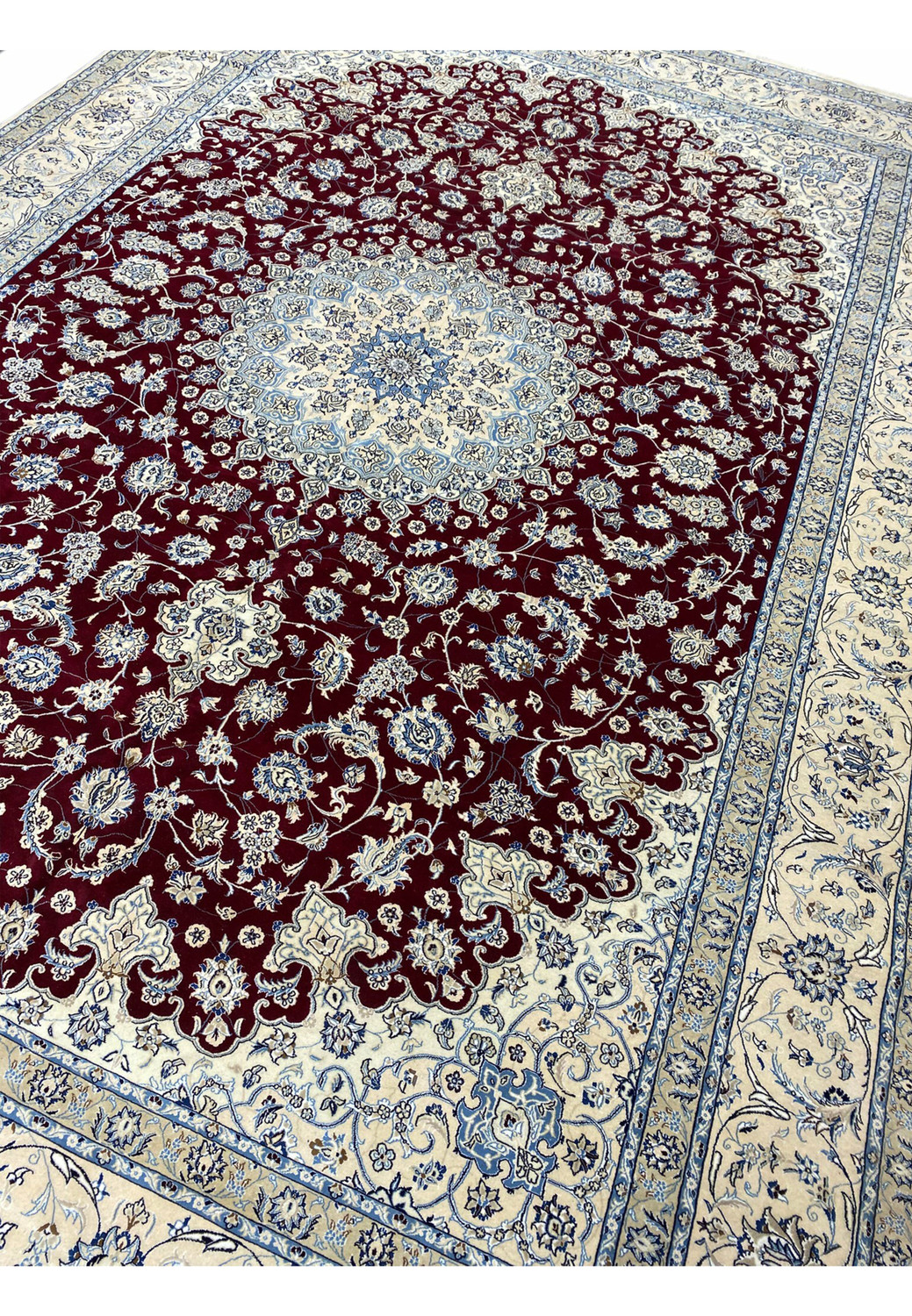Large palace-size red Persian Nain 9 LAA rug shown at an angle with ivory floral borders