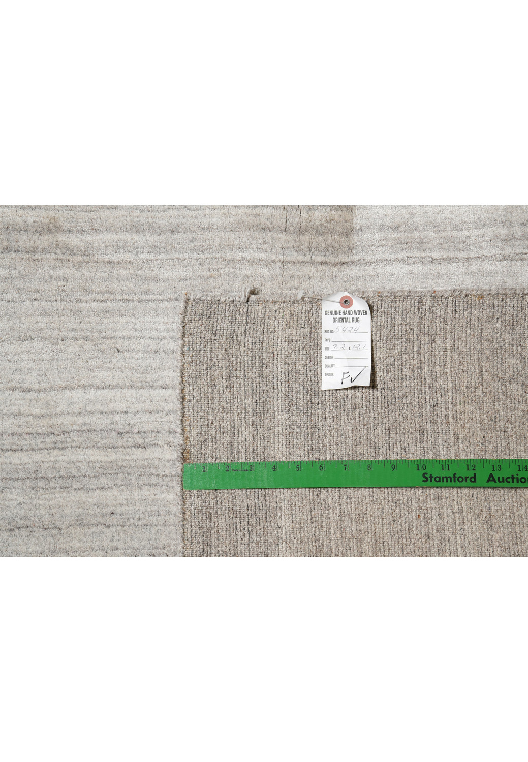 Backside of 9.2 x 12.1 solid gray wool handmade rug showing weave quality and tag