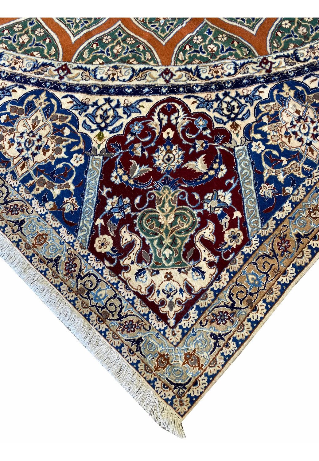 Edge view of the Nain 6La Persian rug focusing on its intricate hand-knotted border of navy, gold, and ivory floral vines, finished with tightly woven fringes for an elegant frame.