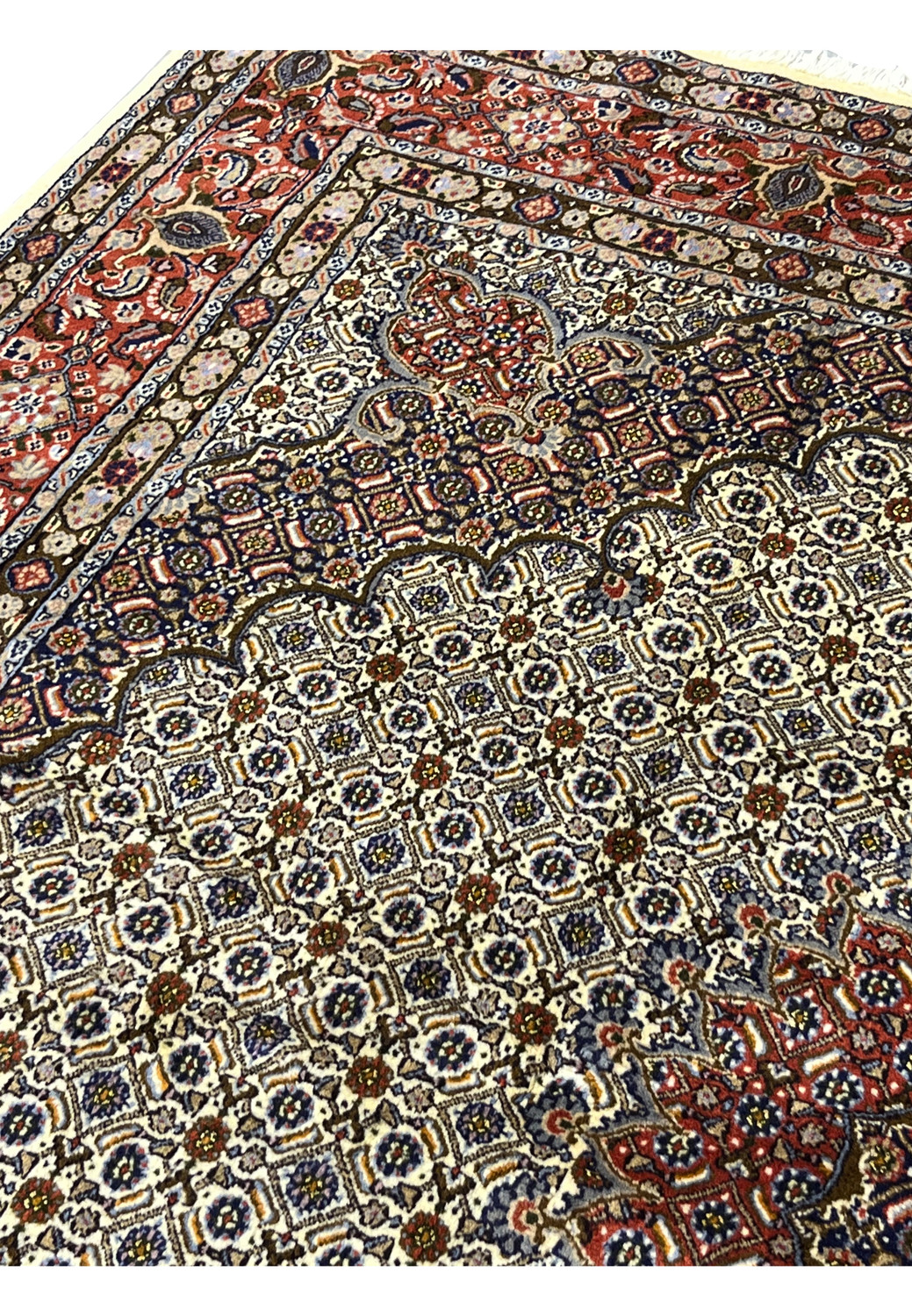 Upper edge detail of the rug’s refined floral border, where ivory and red motifs blend with gold outlines and navy framing, exemplifying Persian border artistry.