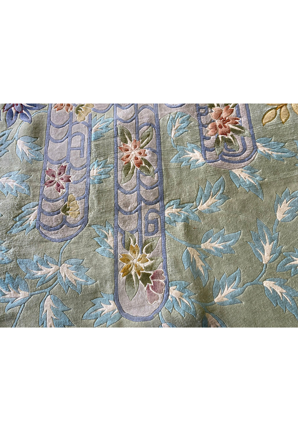 Macro photo of the Art Deco rug’s pastel floral patterns and curved lattice motifs in blue and lavender, accentuating the precision of the handwoven wool and color layering.