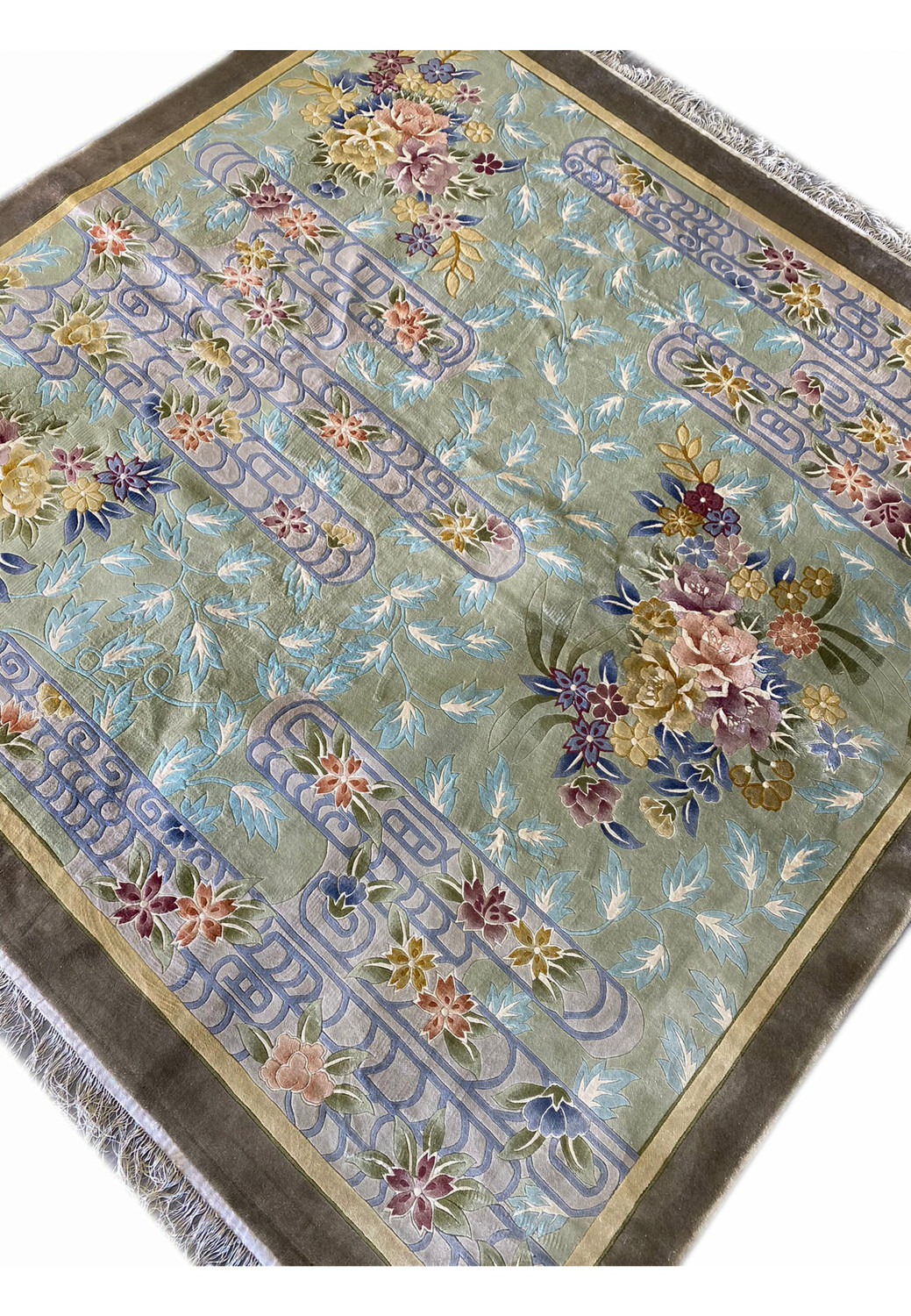 Angled perspective showing the sheen of the wool pile and the intricate balance between geometric scroll lines and organically flowing flowers rendered in Art Deco style.