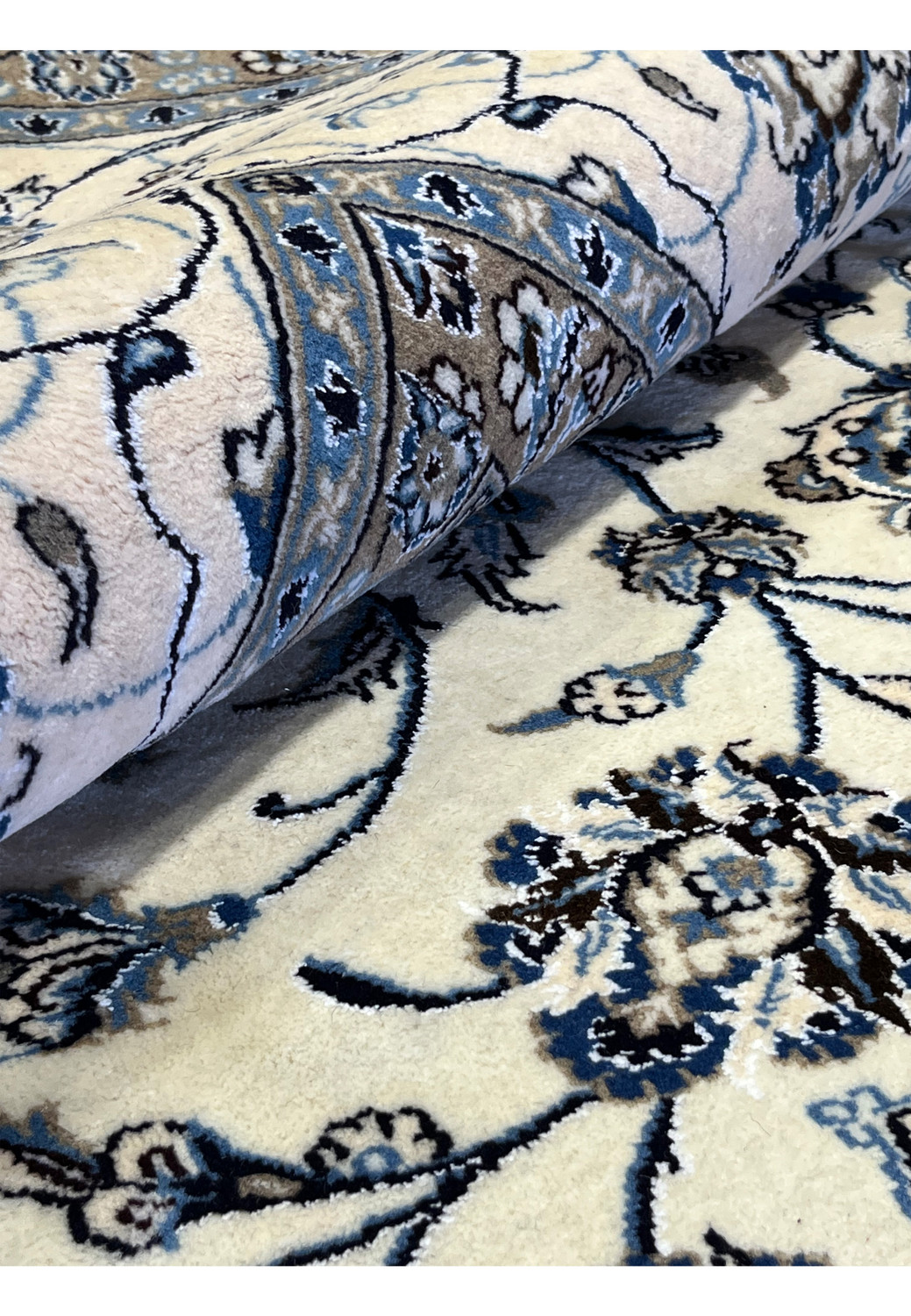 Rolled 10x13 Persian Nain 9LA Rug highlighting ivory and blue field with silk shimmer and fine floral detailing.