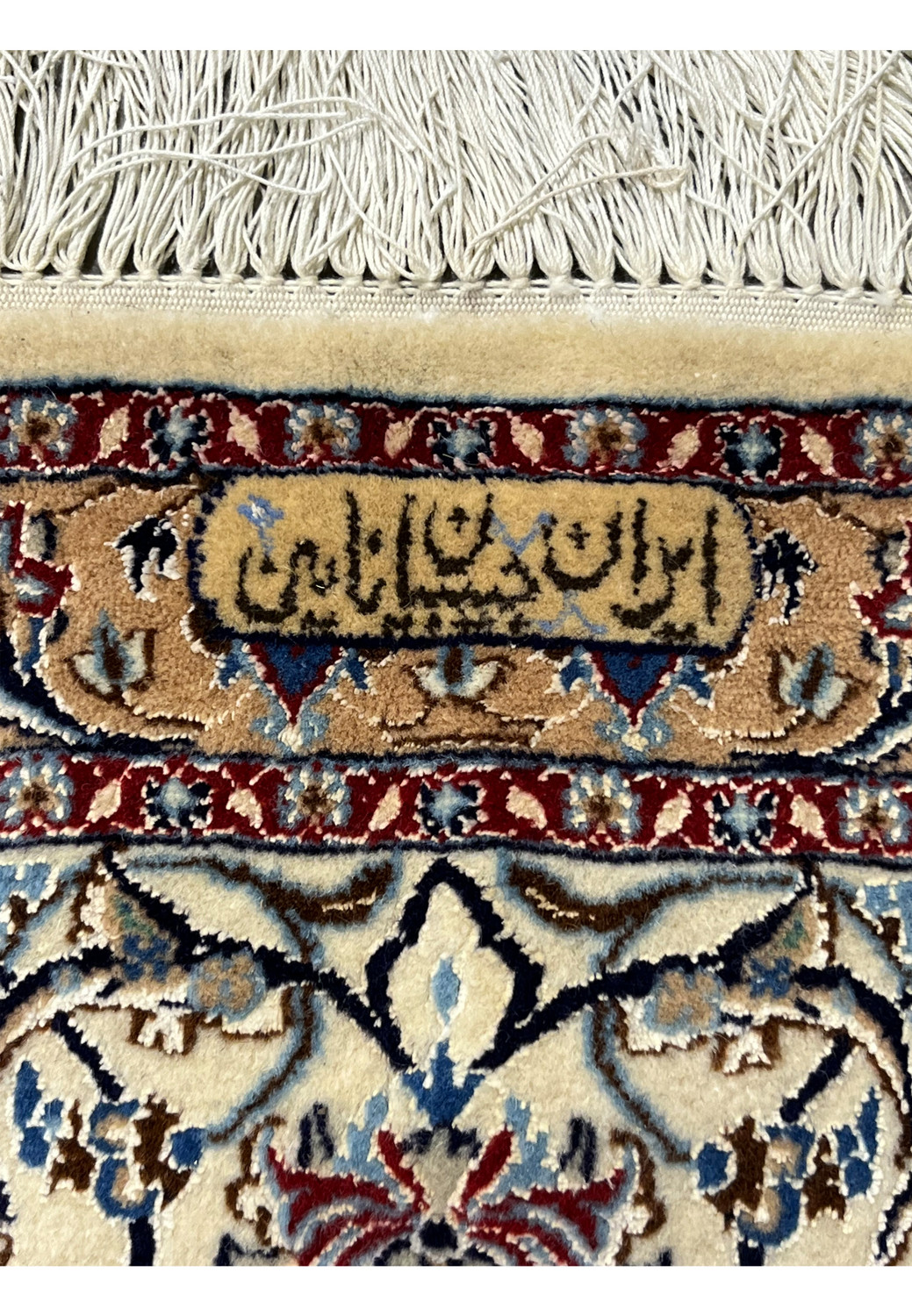 Signature panel of the 5'8" × 9' Persian Nain 4 LA Habibian rug, displaying the weaver’s mark woven into the border in tan, navy, and red silk-outlined lettering.