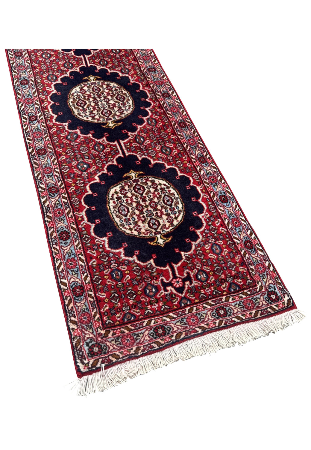 Bottom edge of runner with white fringe, ivory border blossoms, and dark red field filled with navy and gold highlights.