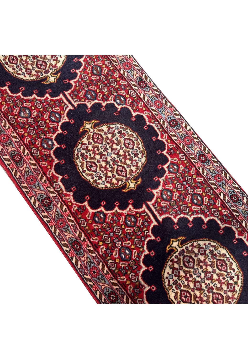 Mid-section of Persian Bijar runner showing red background with navy-blue medallion and tiny ivory, rose, and turquoise motifs.