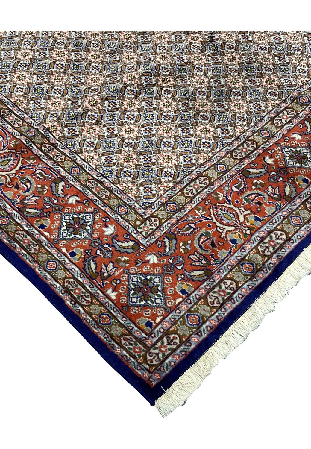 Corner view showing precise hand-finished fringe and navy edge framing red and ivory Moud motifs.
