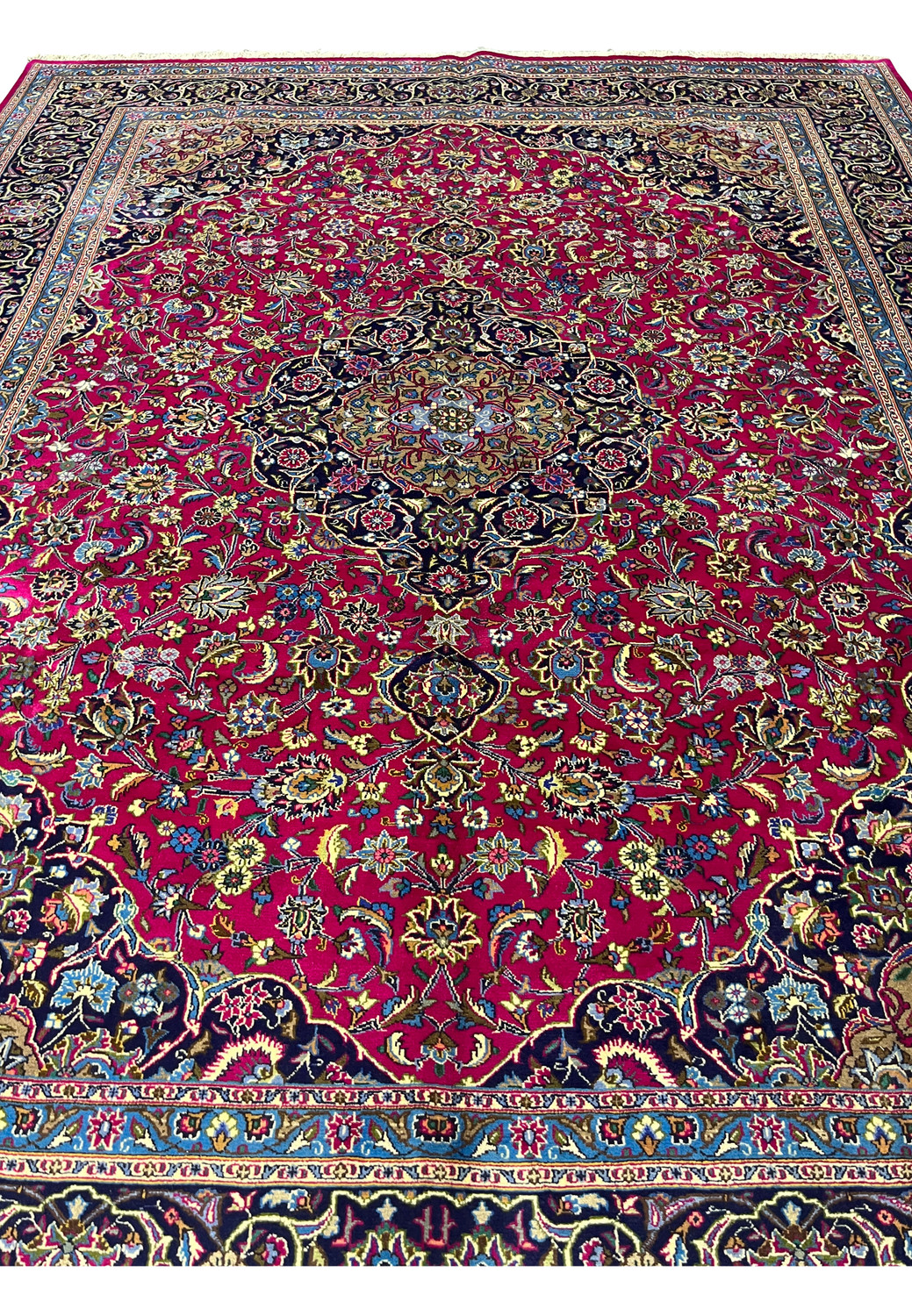 Top full view of Persian Mashad red wool rug showing floral medallion and navy borders.