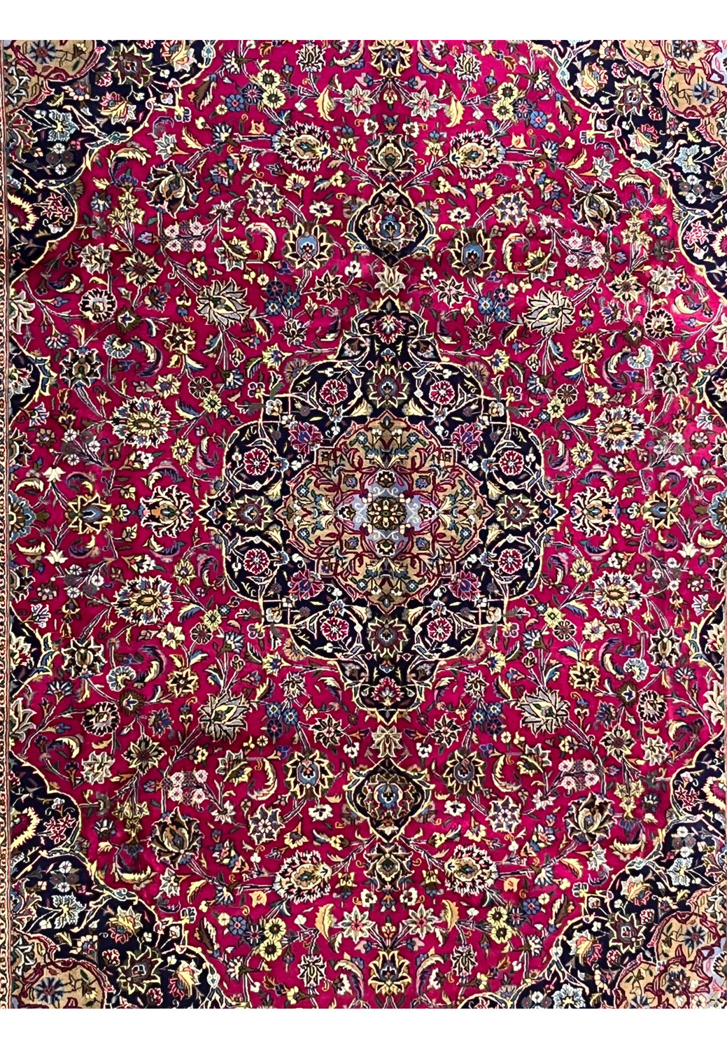Central field close-up of Mashad rug highlighting ruby red background and intricate floral motifs.