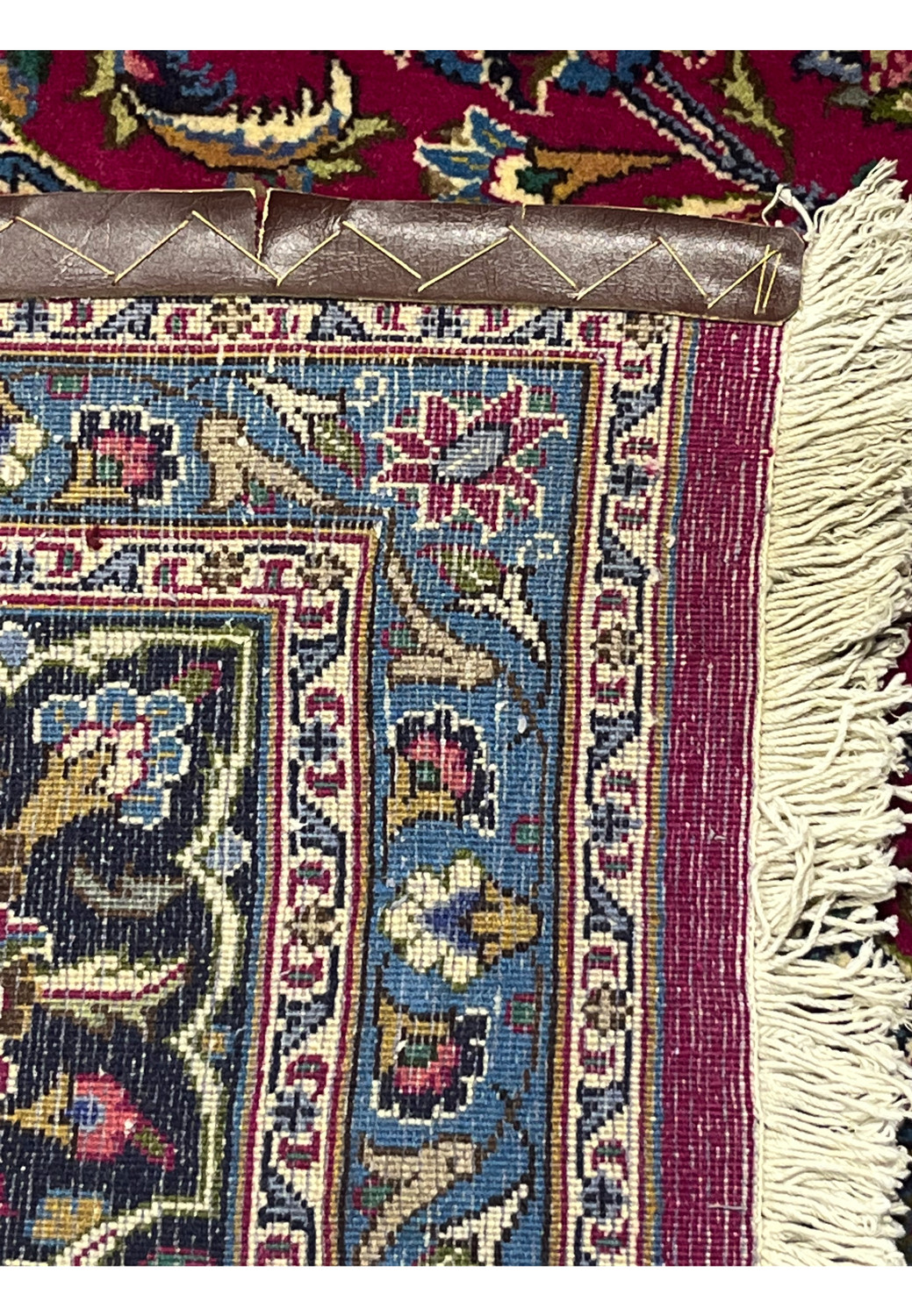 Backside of 9'9x12'8 Persian Mashad rug showing fine knotting and detailed craftsmanship with blue and red tones.