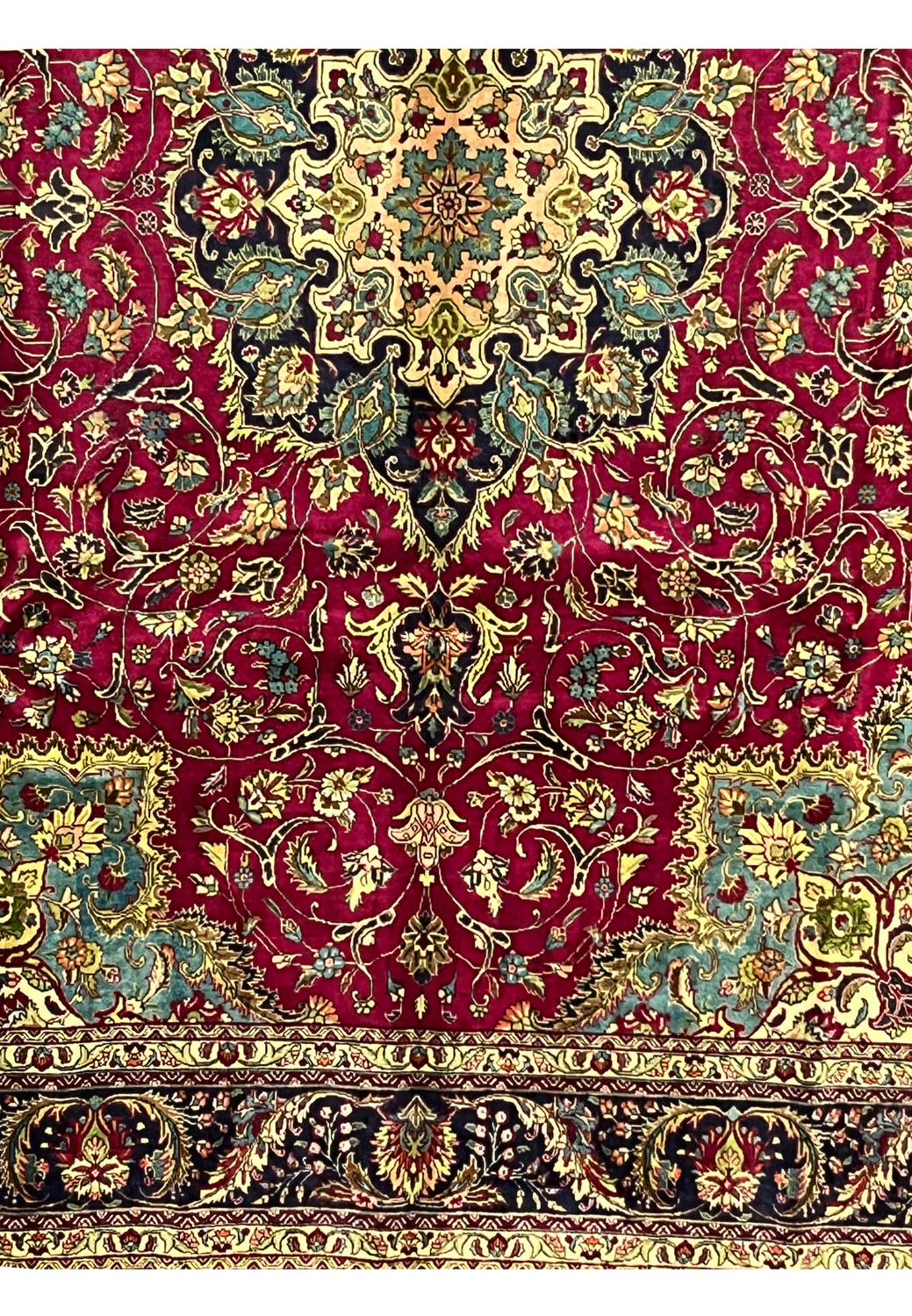 lower section of Persian Tabriz rug showing floral layout, rich red field, and multi-toned corner design