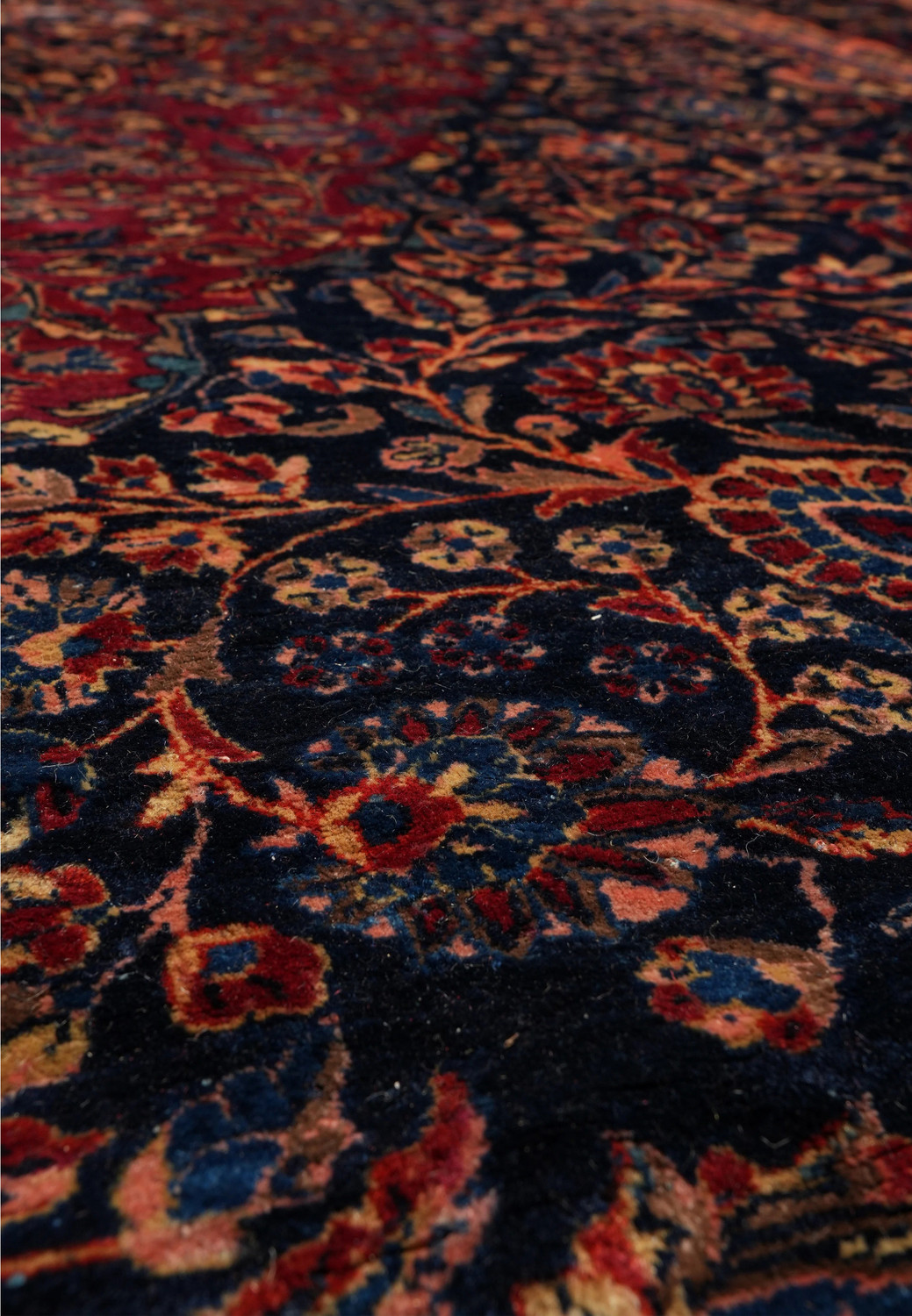 Closeup of floral motifs on the deep navy field of the 12'7 x 19'5 antique Persian Kashan rug showing detailed blossoms and warm accent colors.