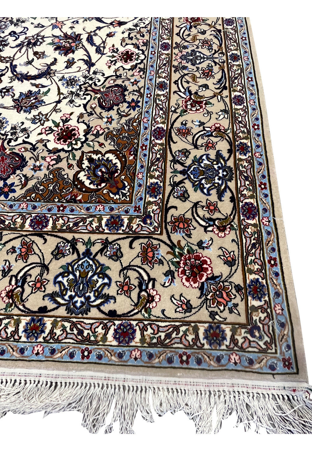 Border close-up with beige ground, navy floral motifs, and light-blue highlights from the Isfahan rug.