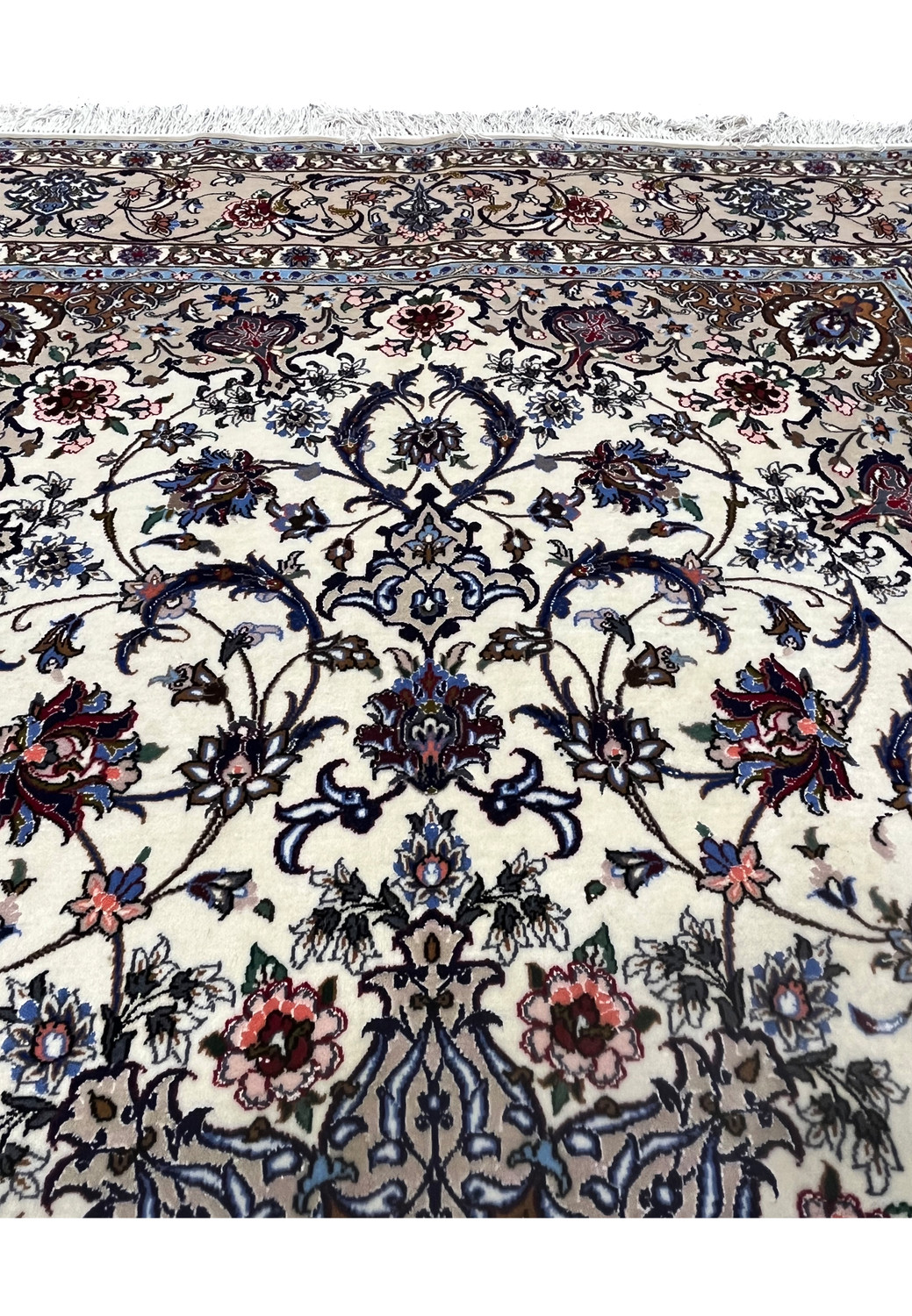 Close-up of floral motifs on the Davari Isfahan rug featuring navy scrolls, pink blossoms, and silk highlights on an ivory wool field.