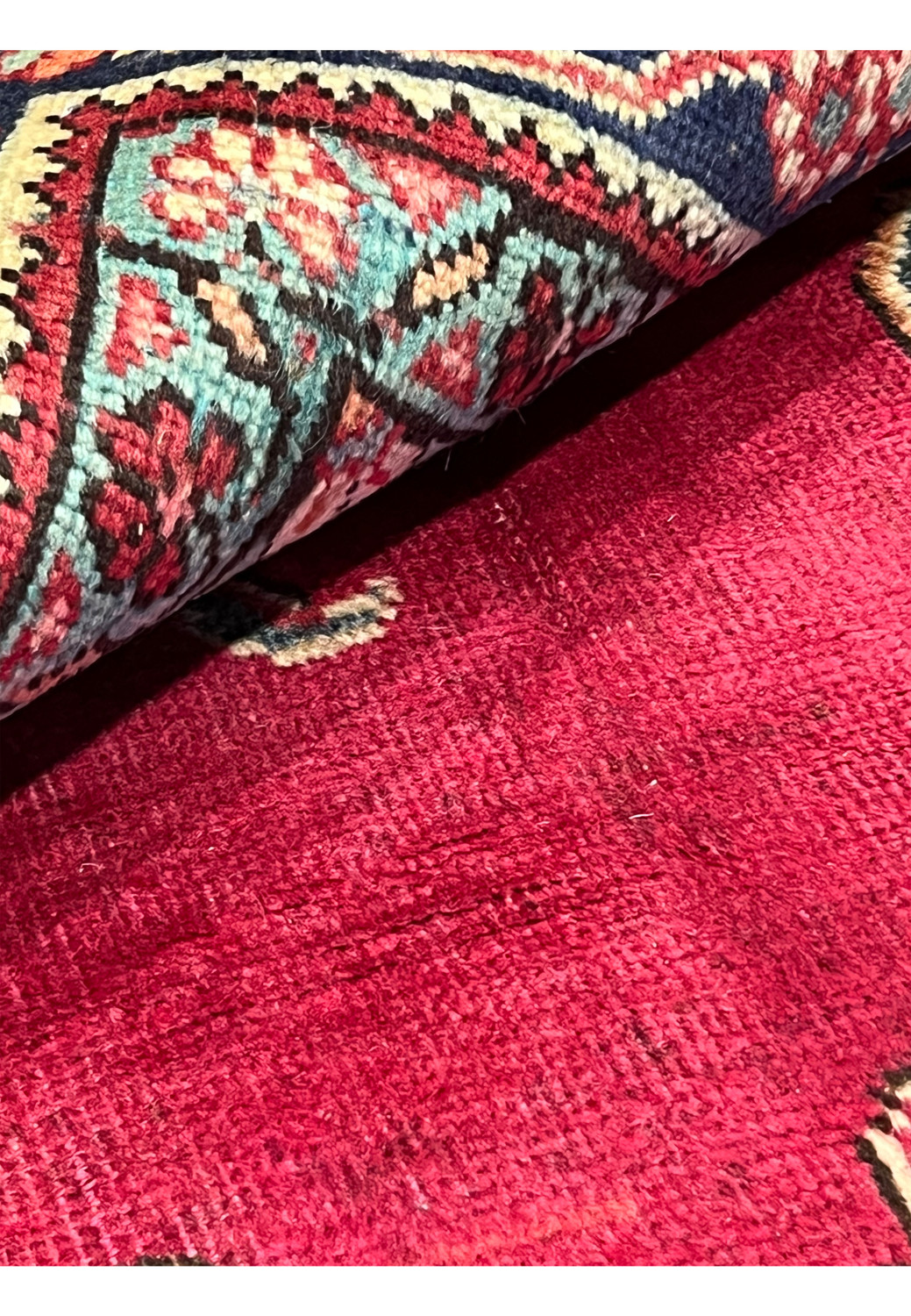 Detailed closeup of low-pile patina on Persian Tabriz rug with faded red wool and visible wear consistent with vintage character.