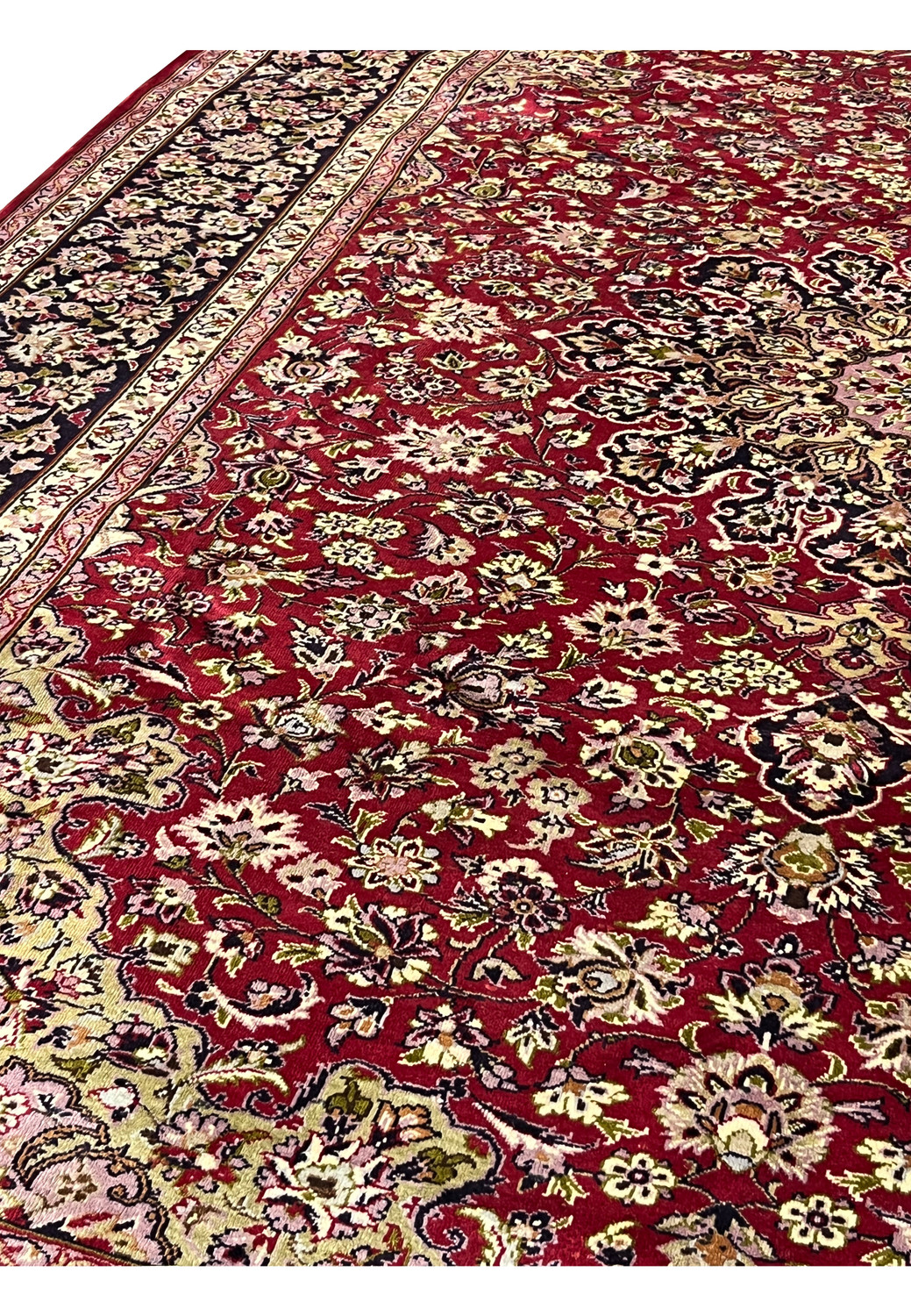 Close-up of floral patterns on red Persian Isfahan rug showing detailed blossoms, scrolling vines, and soft pastel highlights across the field.