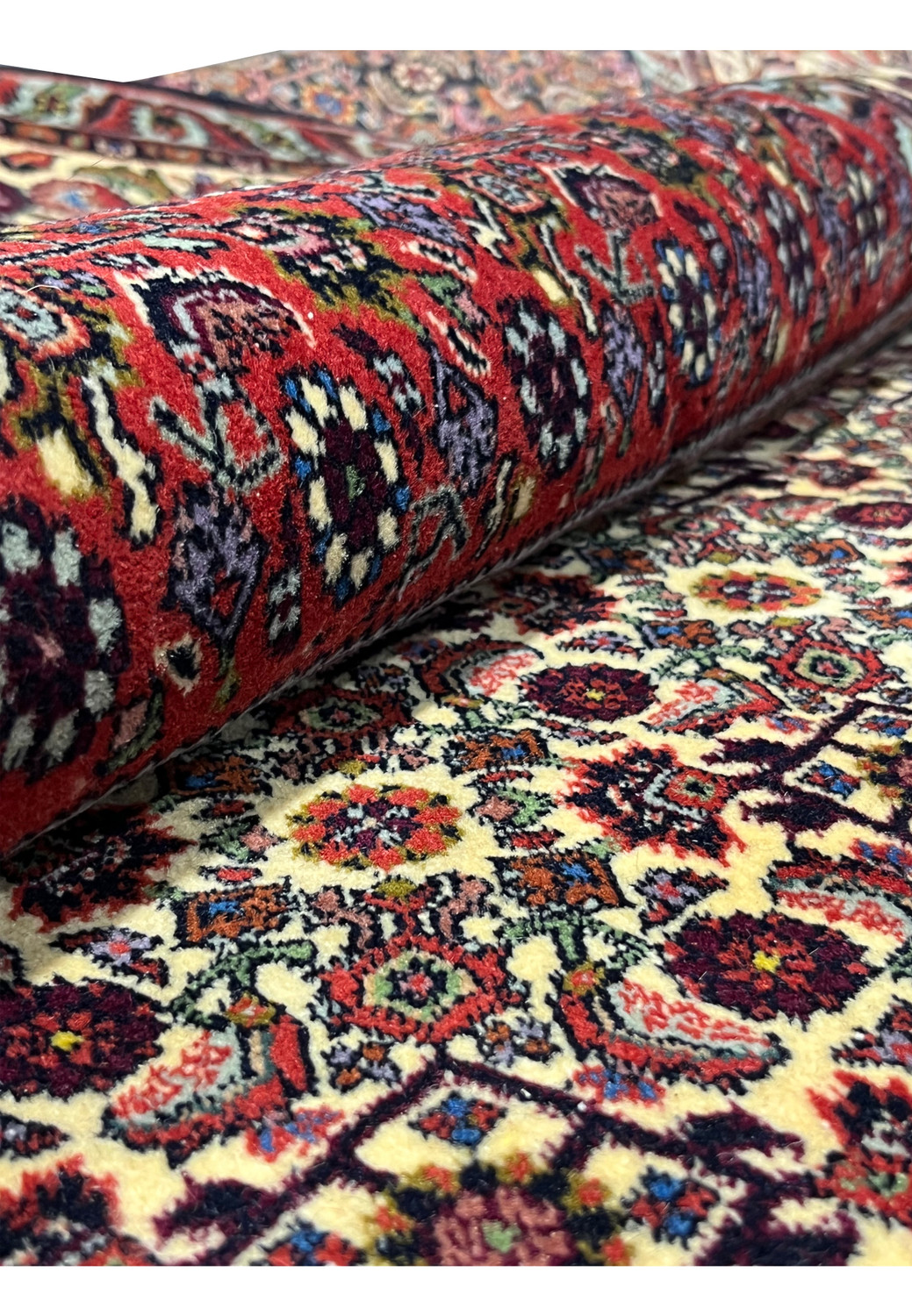 Rolled 10x13 Persian Bijar rug showing thick dense pile and rich red geometric wool patter