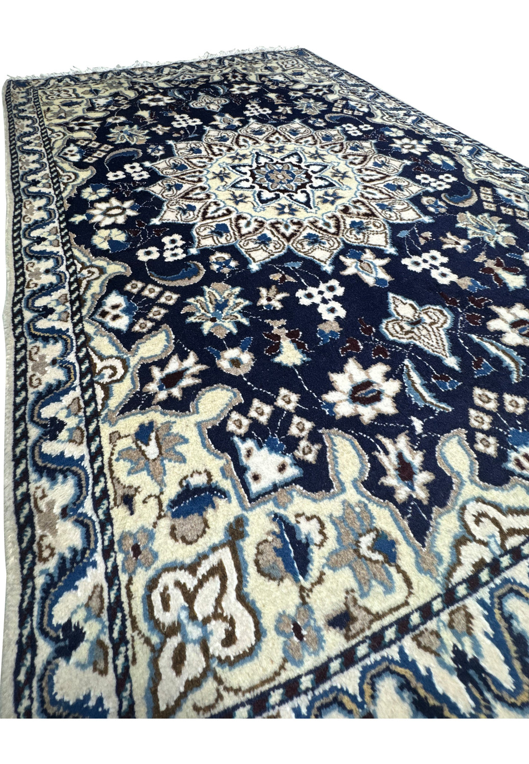 Angled view of royal navy Persian Nain rug showing wool texture and ivory medallion