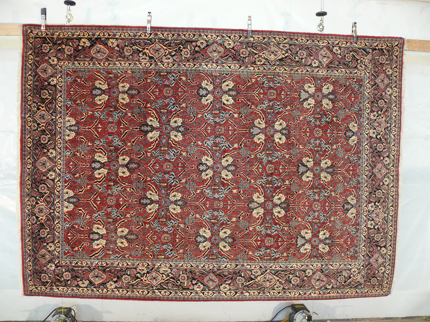 Hanging view of floral Bijar iron rug showing brick red background, ivory palmettes, navy vines, and dense wool texture