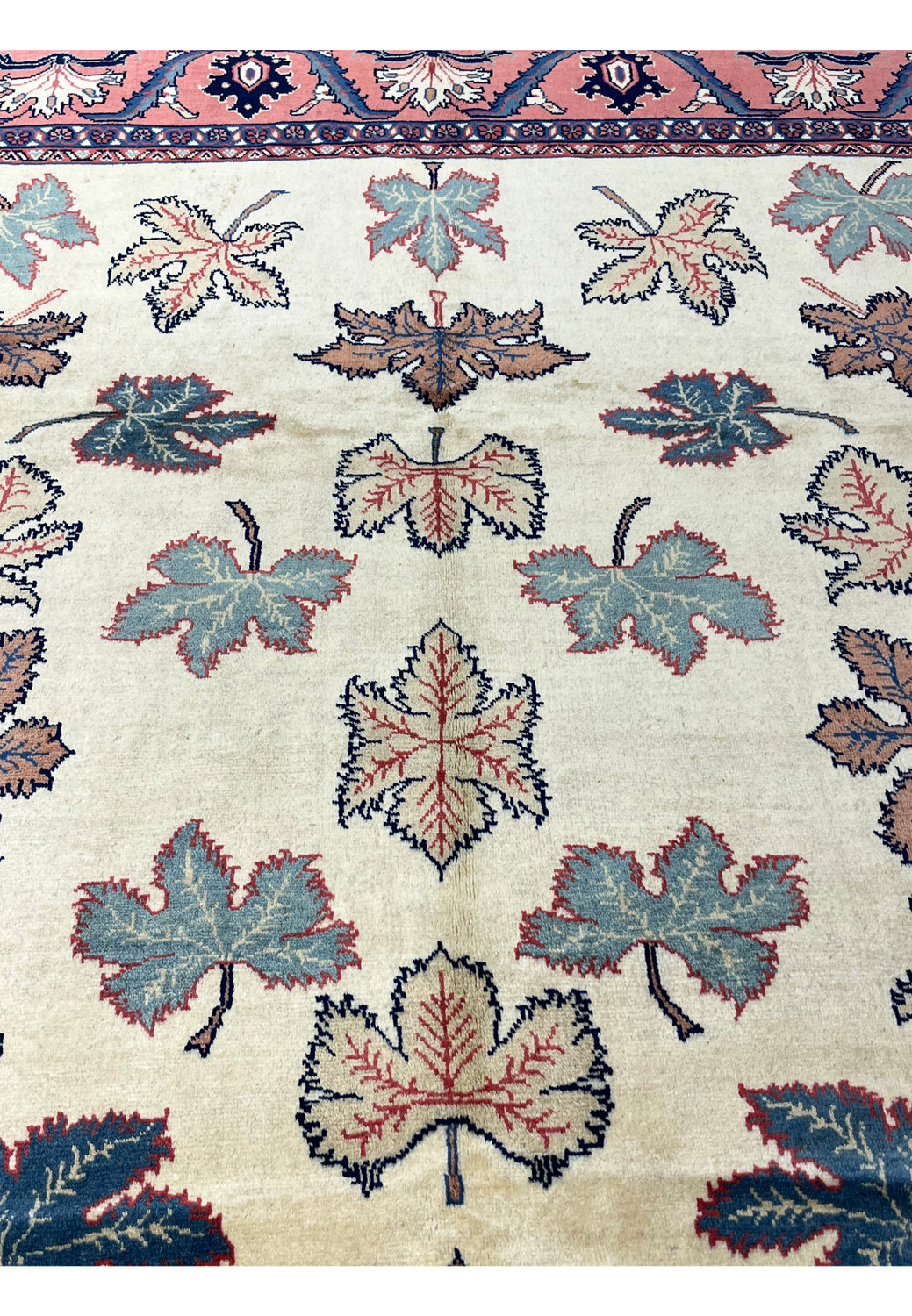 Close view of botanical leaf motifs on an ivory Persian Farahan rug showing fine outlines and color variation