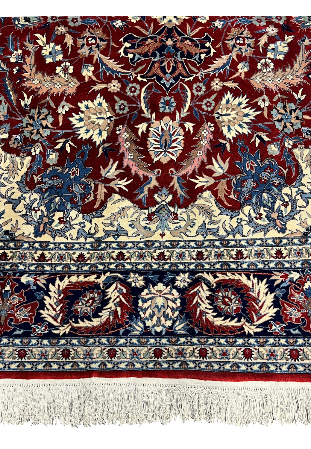 Lower border detail of Persian Isfahan rug showing navy floral guard borders, ivory accents, and hand knotted wool fringe