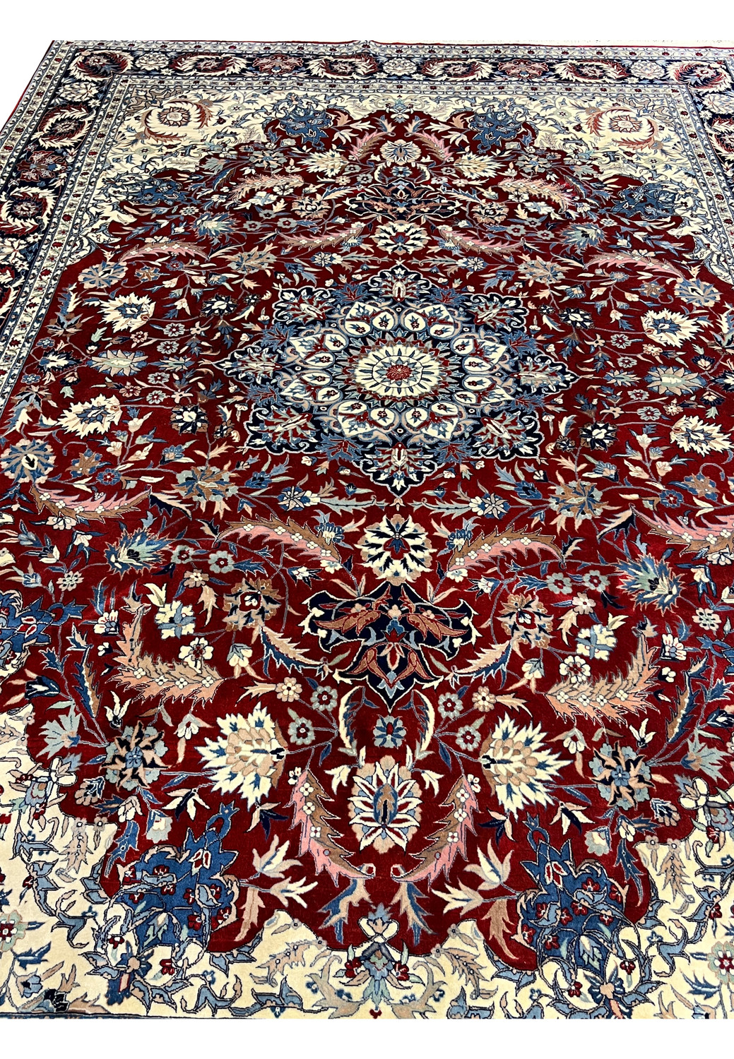 Top view of Persian Isfahan rug with symmetrical floral design, finely detailed medallion, and balanced red, ivory, and blue colors