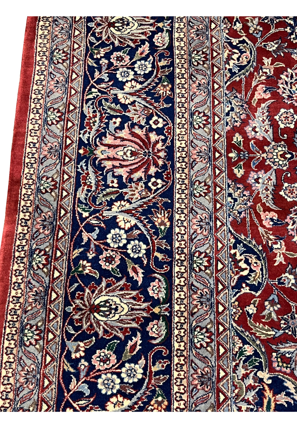 Side border close-up showing floral motifs on navy Kashan rug border