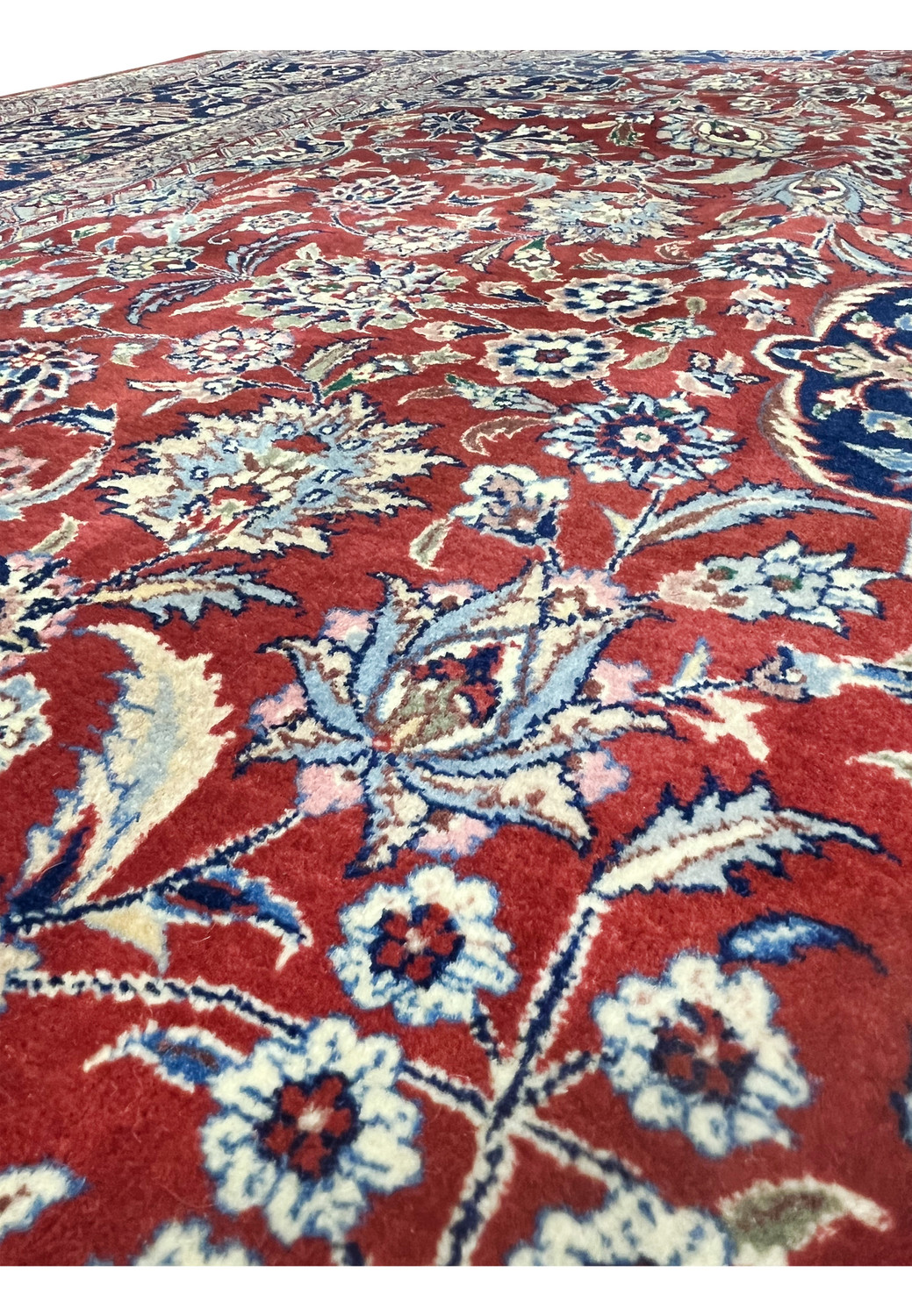 Close-up of red field on antique Persian Kashan rug showing layered floral vines and precise hand-knotted wool texture