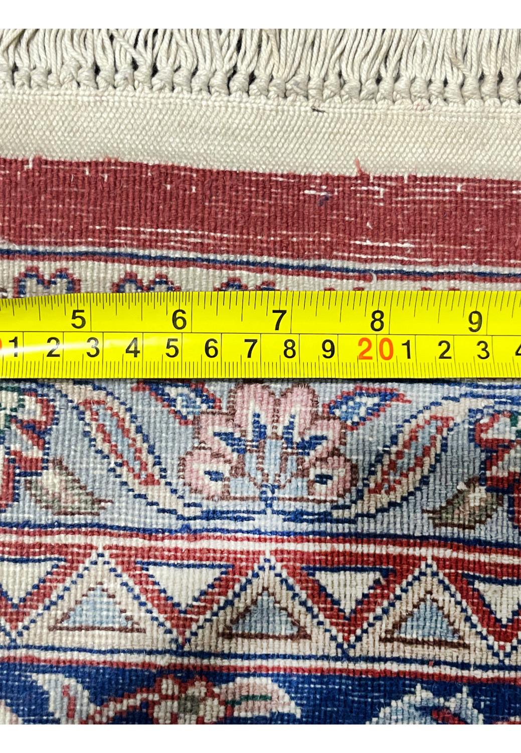 Backside of antique Persian Kashan rug with ruler showing knot scale, density, and weaving precision