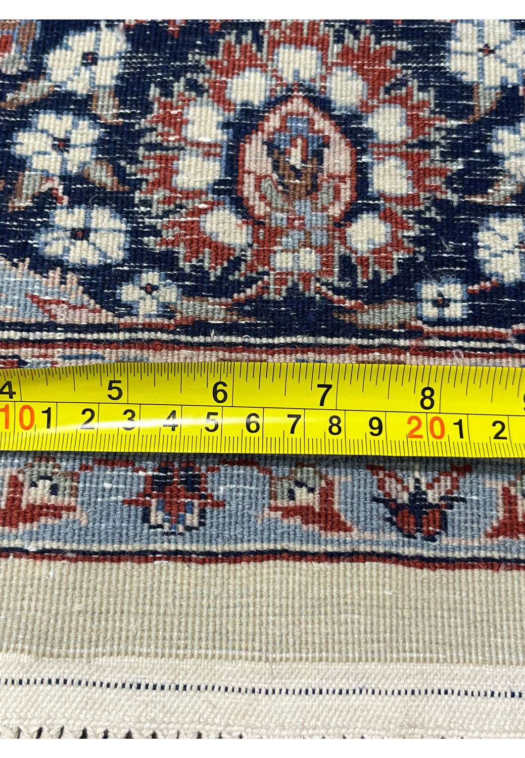 Persian Tabriz rug backside close up with measuring tape showing knot density and precise hand knotted construction