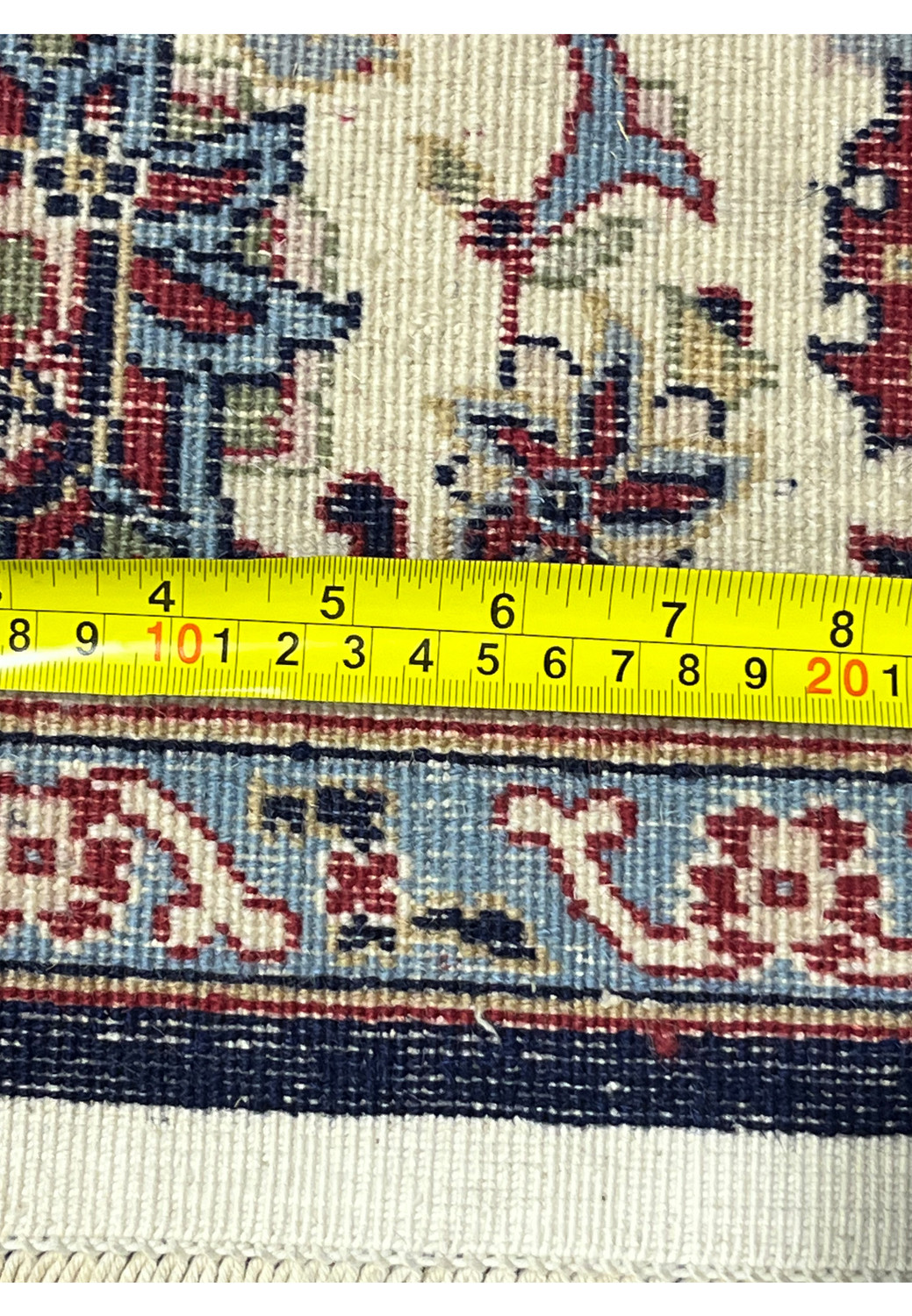 Backside of a navy blue Persian Sarough kork rug with measuring ruler showing precise weave density and straight selvedge alignment