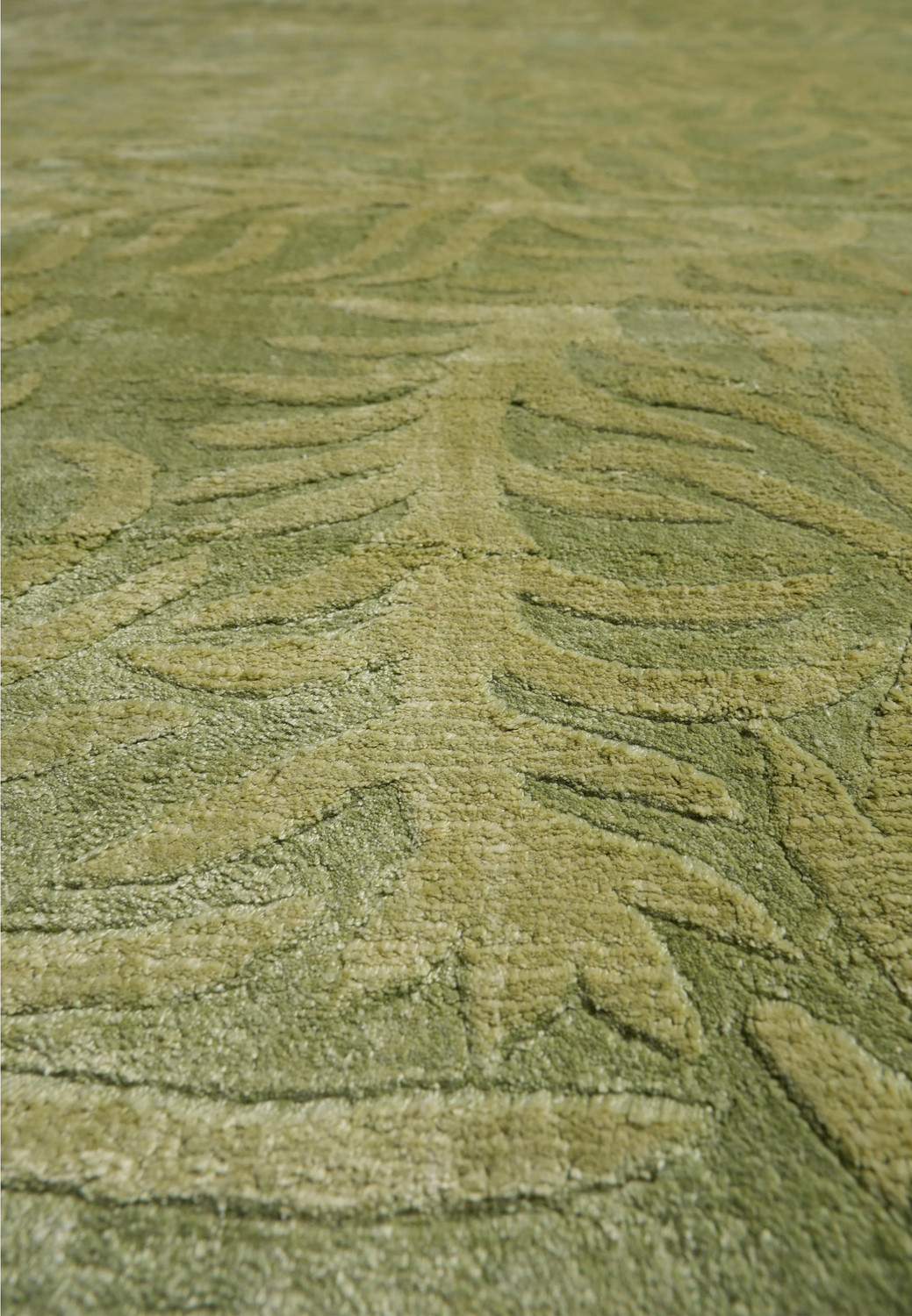 Detailed view of the botanical motif with layered olive and sage tones and soft silk highlights across the rug surface.