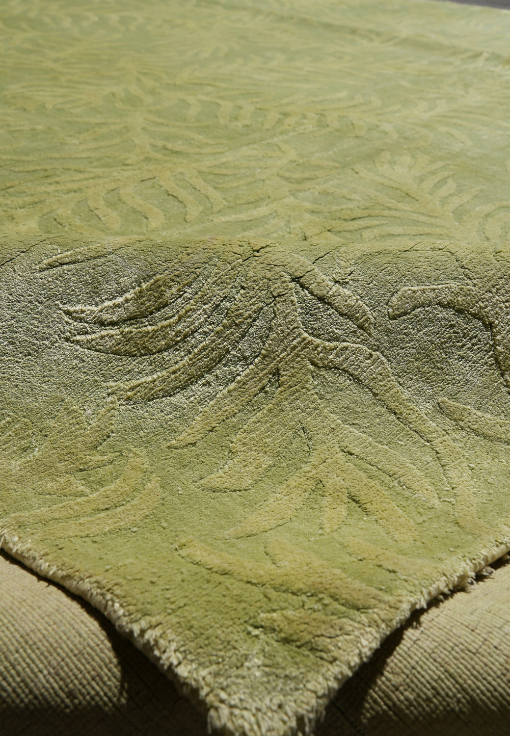 Edge close-up showing clean finishing and the seamless borderless design of this modern wool and silk green rug.