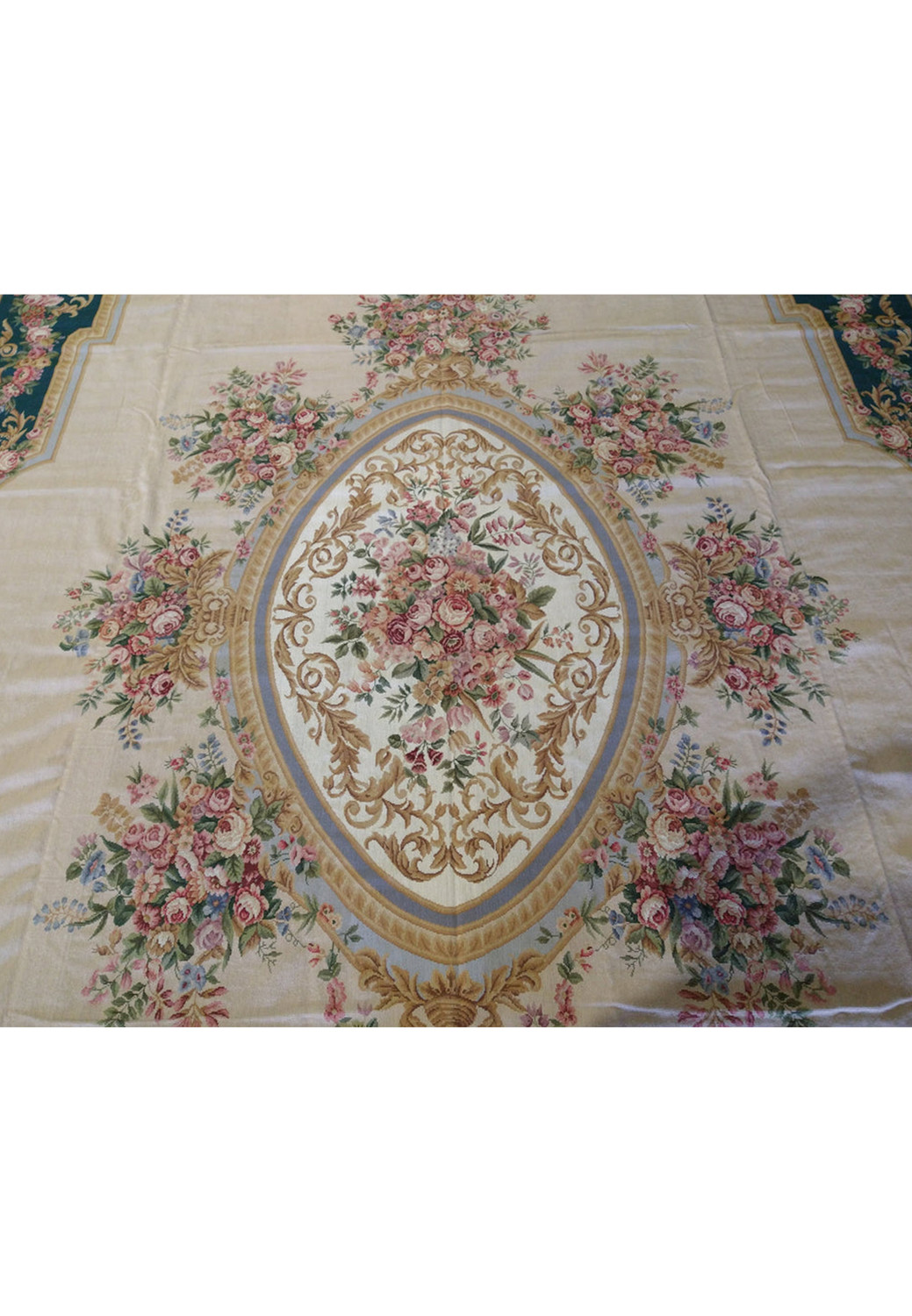 Upper medallion area of French Aubusson rug with floral bouquets, oval framing, muted gold scrolls, and soft pastel botanical accents