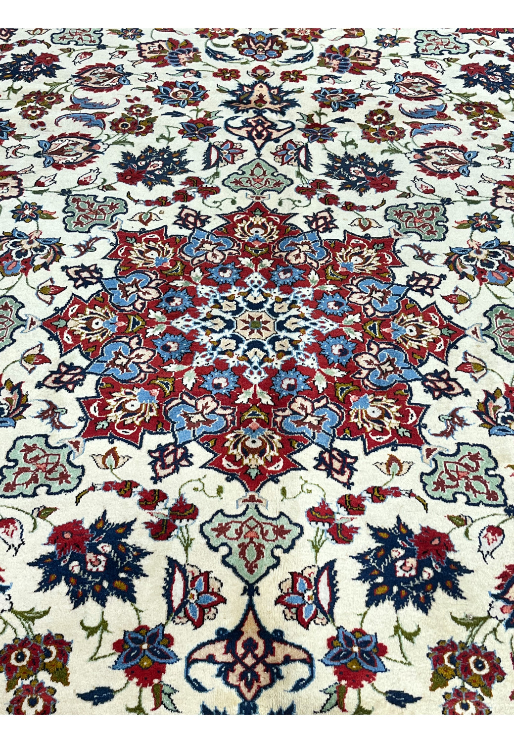 Closeup of the central medallion on a Persian Isfahan rug featuring layered floral geometry, silk highlights, ivory field, and precise kork wool weaving.