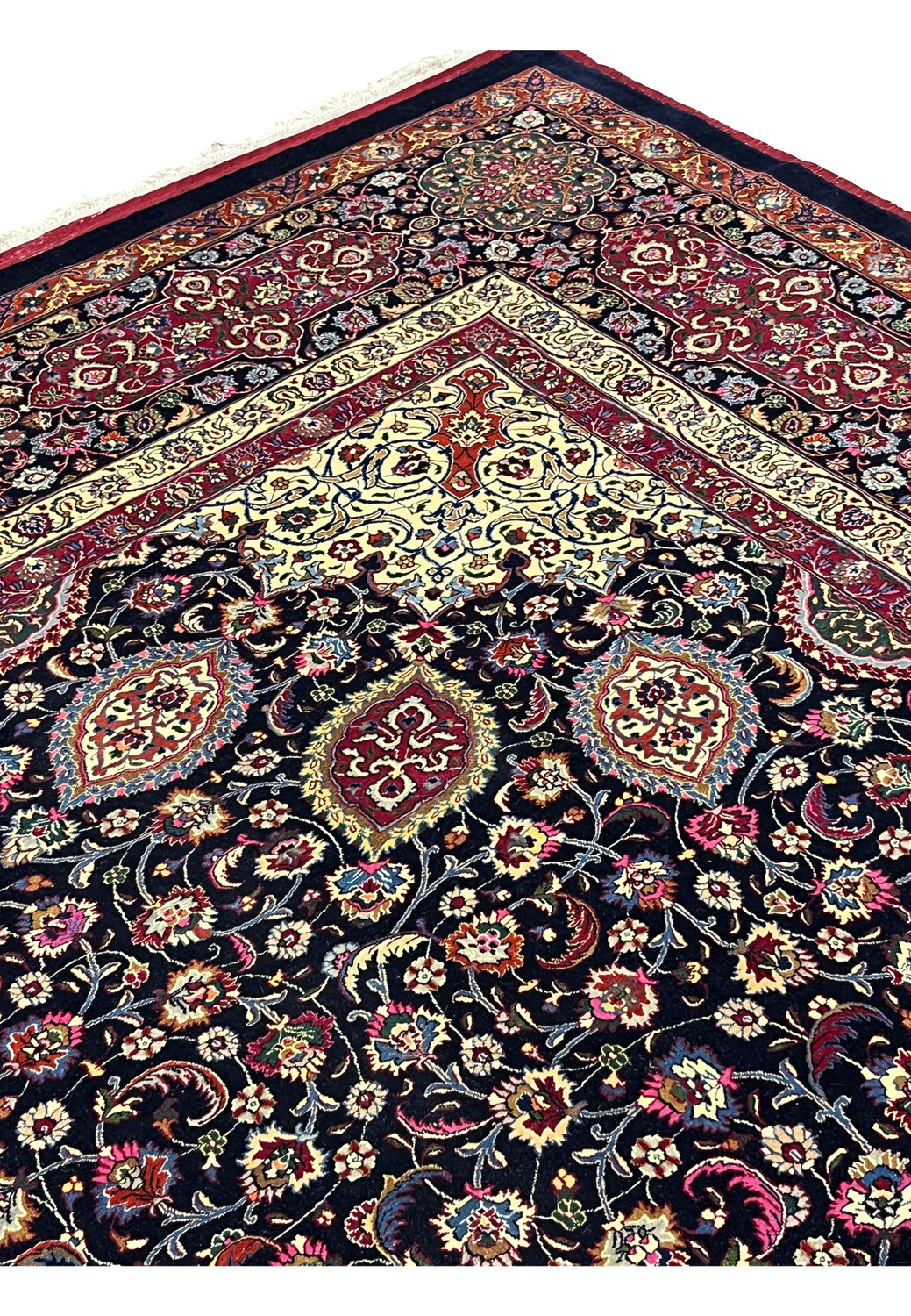 Upper section of Persian Mashad rug featuring symmetrical floral motifs, flowing vine work, deep navy field, and refined silk and kork wool texture