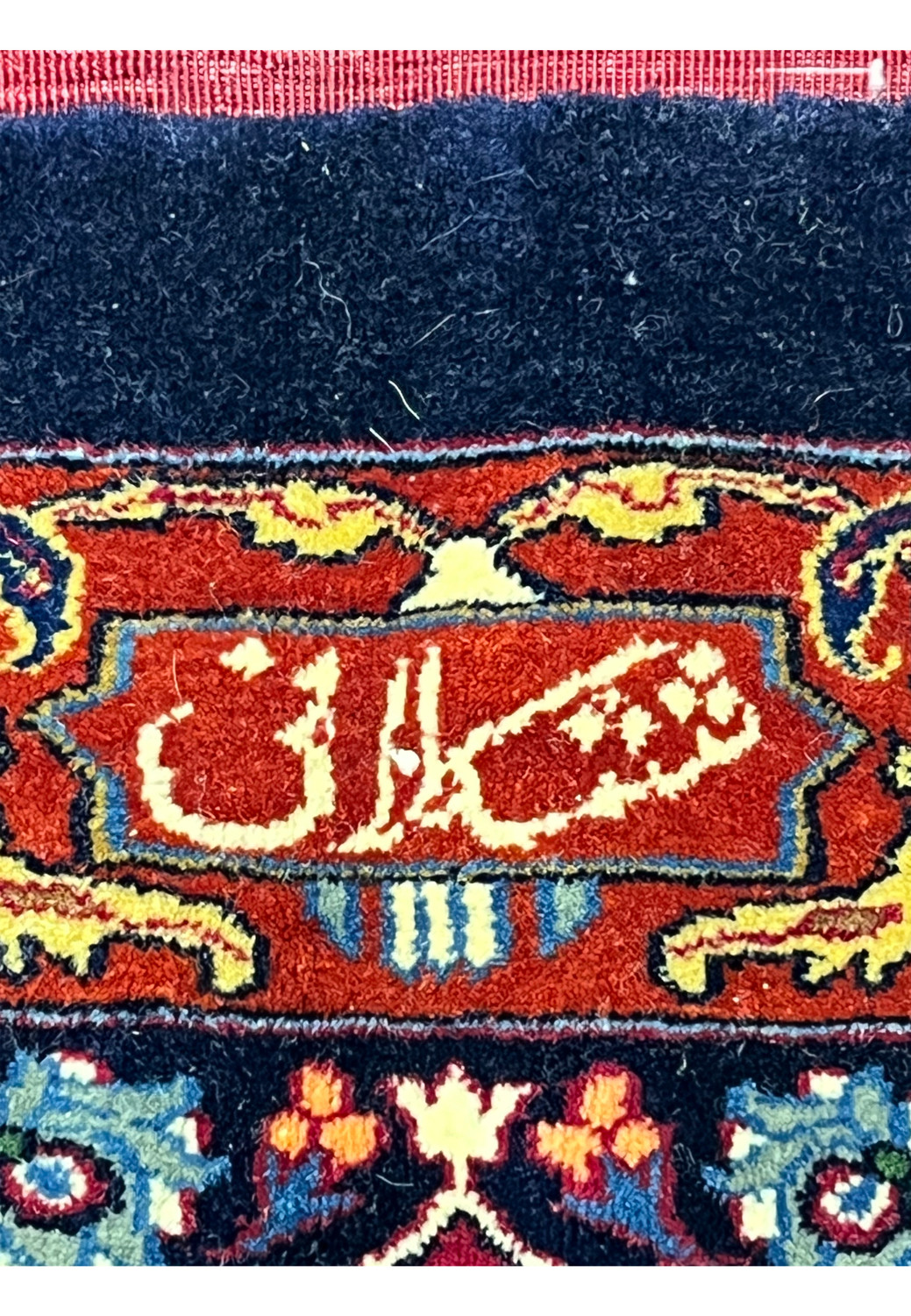 Detailed view of the woven Sheshkalani signature on a large Persian Mashad rug, highlighting fine knotting, silk accents, and traditional floral motifs.