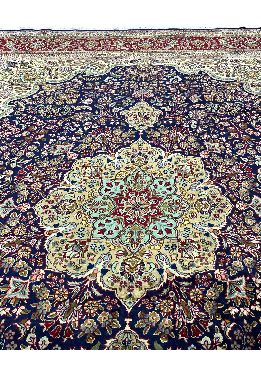 Persian Tabriz rug medallion and surrounding field showing floral symmetry, navy blue ground, ivory structure, and fine hand knotted detail