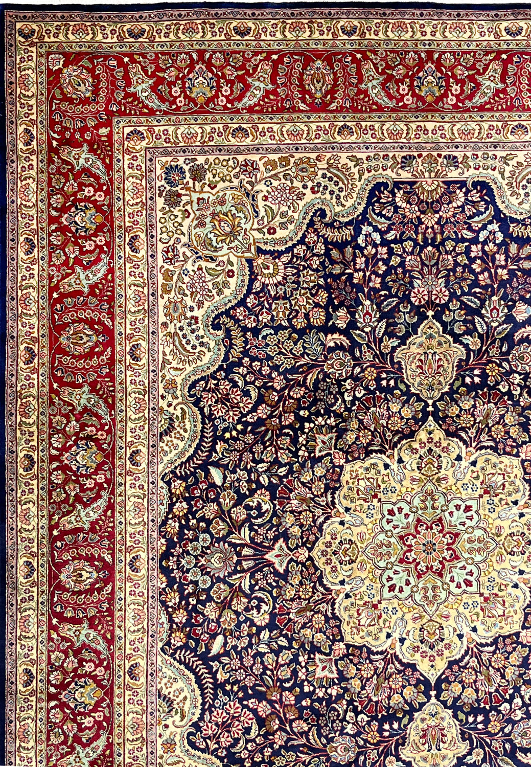 Classic ivory border of Persian Tabriz rug with repeating floral motifs, clean symmetry, and strong contrast against navy ground