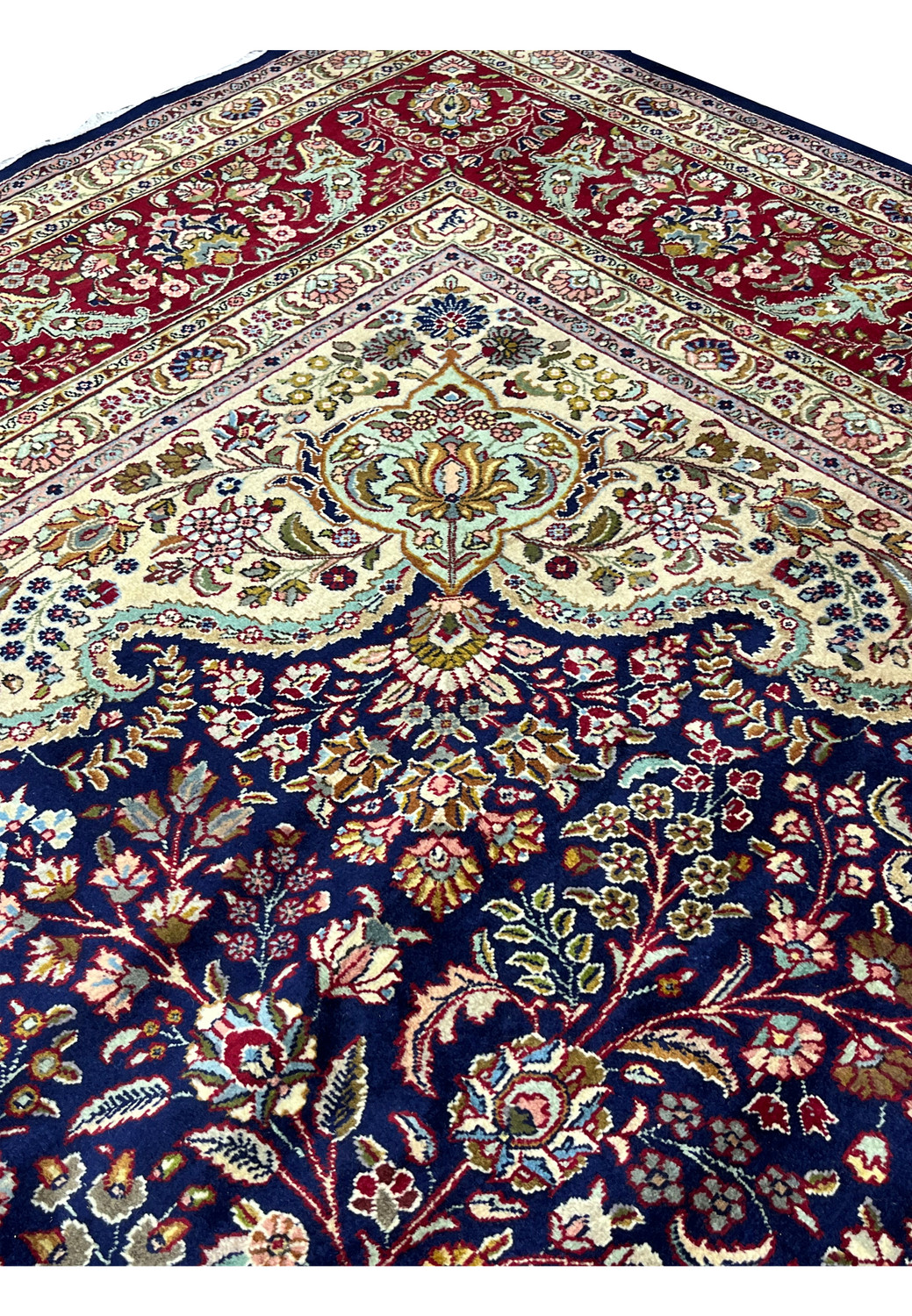Upper edge view of a Persian Tabriz rug with crisp borders, balanced proportions, and finely woven floral elements