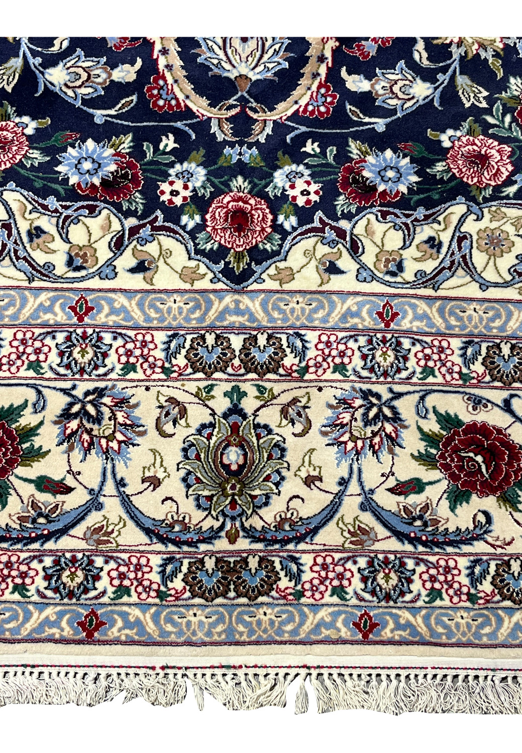 Lower border detail of a Persian Isfahan rug with scrolling floral vines in ivory, powder blue, burgundy, olive green, and navy on a finely knotted foundation