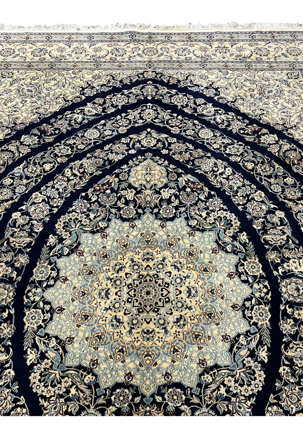 Upper section of Persian Nain 6 La rug showing navy field with scrolling floral vines and silk highlights near the top border