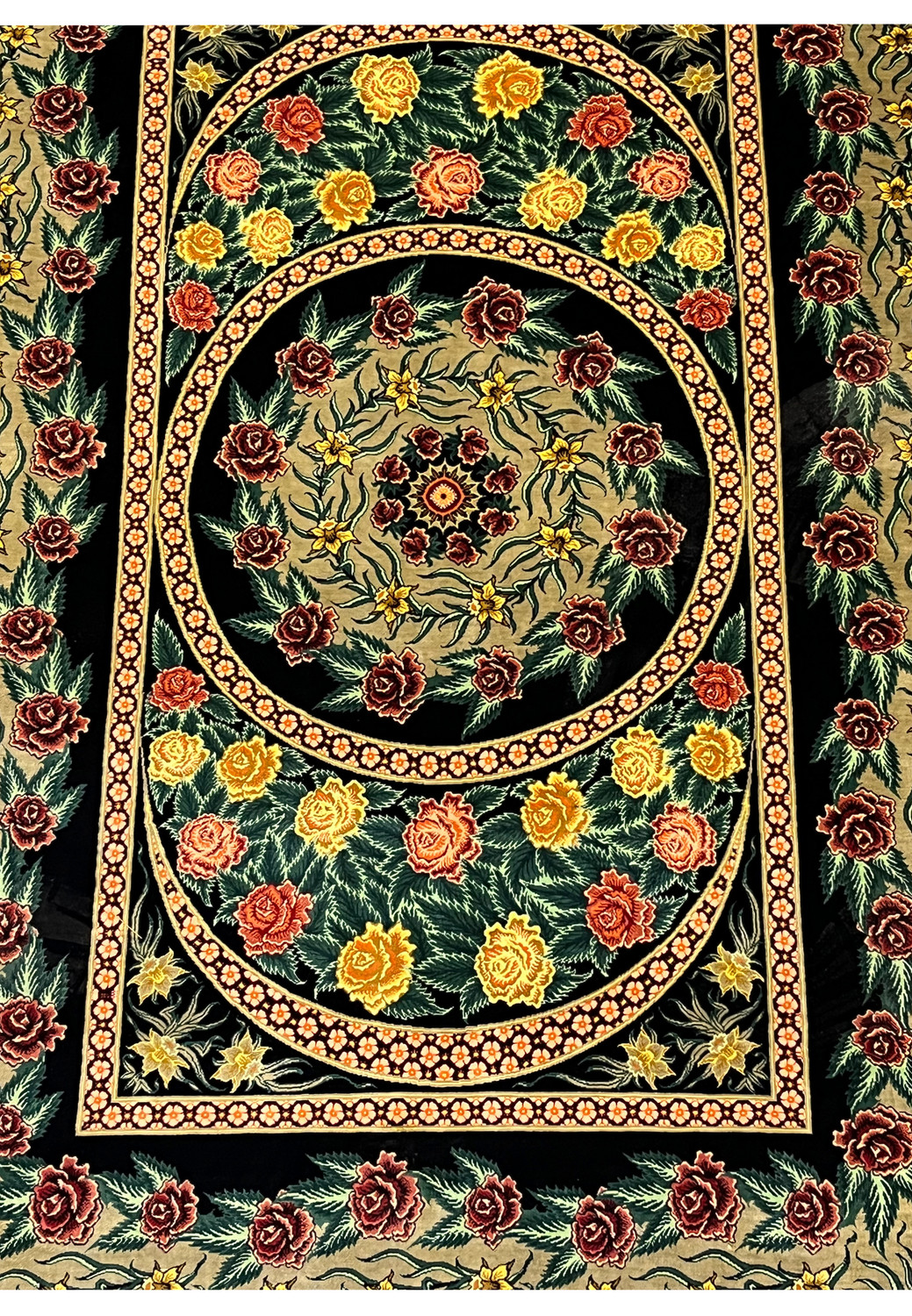 Lower medallion close-up of a signed Persian Qum silk rug showing roses, vine scrolls, and precise silk knot work forming a symmetrical circular composition