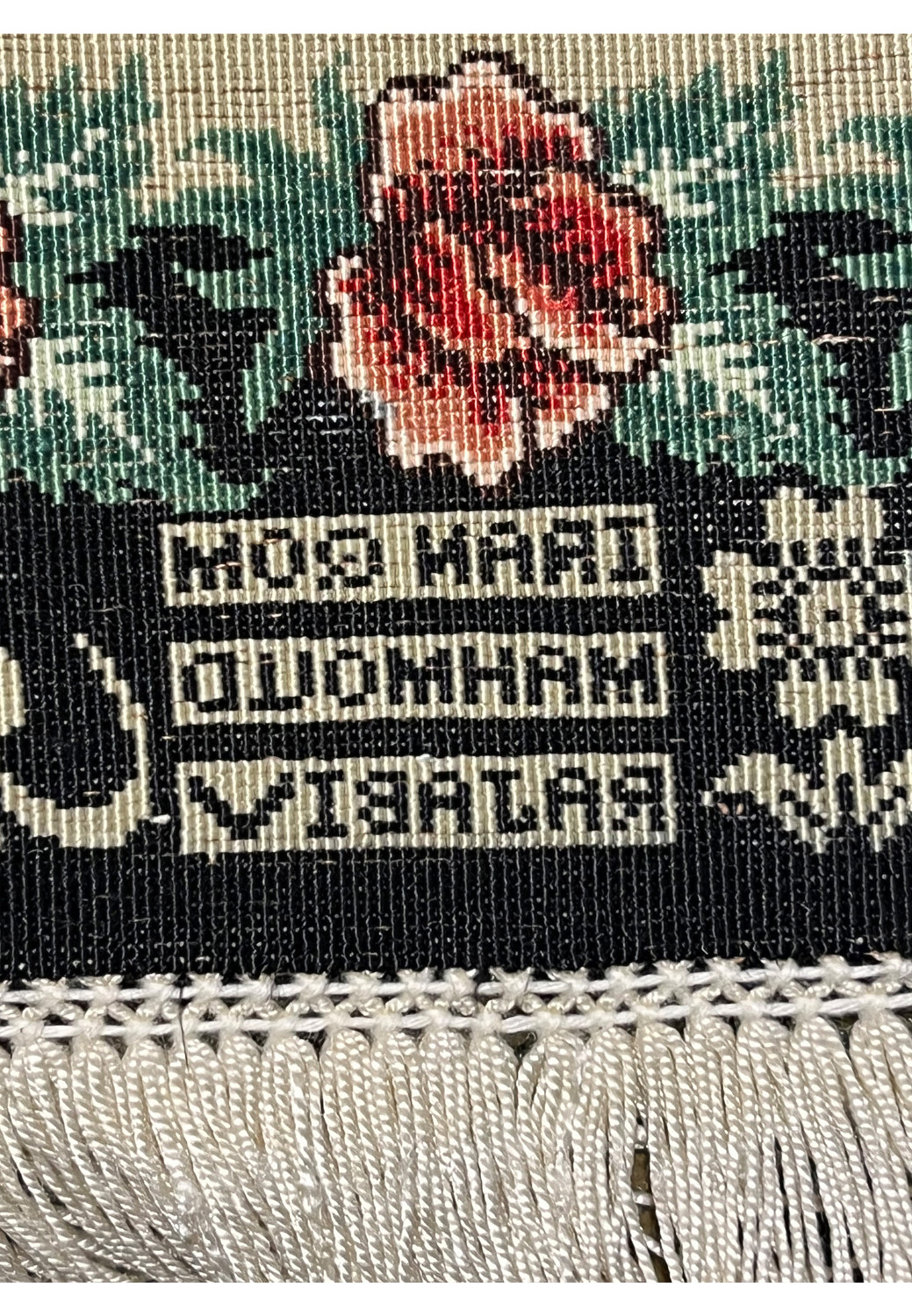 Backside signature detail of a signed Persian Qum silk rug showing Mahmoud Rajabi inscription woven into the design above the fringe