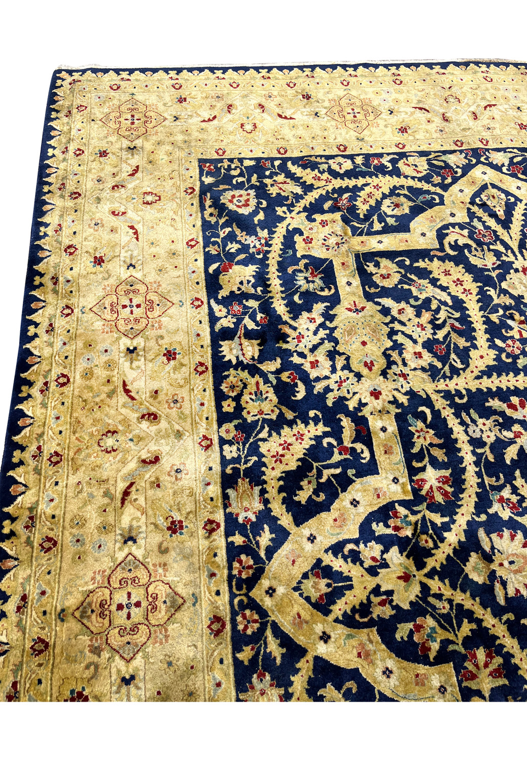 Upper border section of a distressed Agra rug from India featuring floral motifs, muted reds and greens, softened pile, and stabilized edge repairs