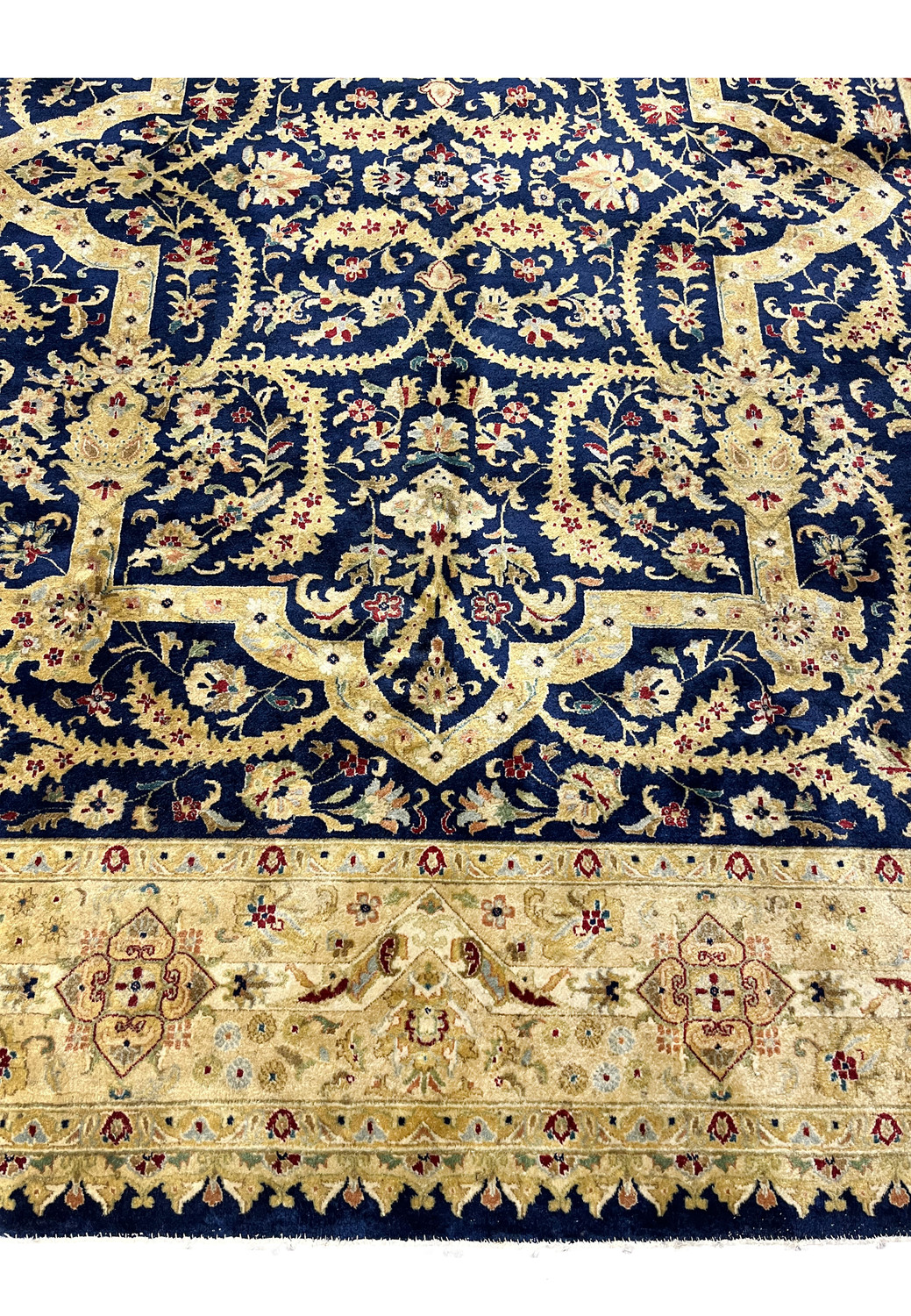 Lower border close-up of a worn Indian Agra rug showing antique gold tones, floral cartouches, softened reds, and visible age-related patina