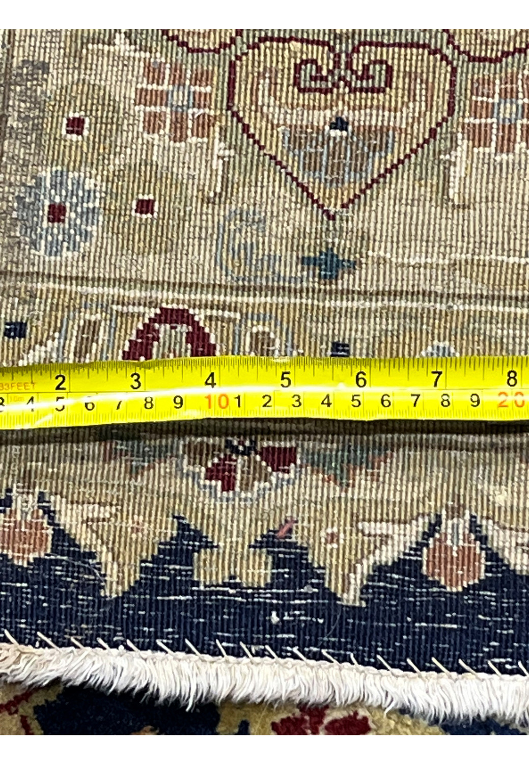Backside of a distressed 8' x 10' Oriental Agra rug made in India, photographed with measuring tape to show scale, visible wear, repairs, and aged handwoven structure