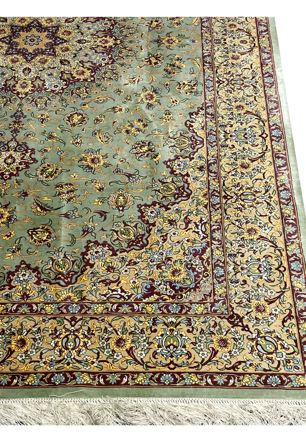 Close-up of the main border on a signed Mirmehdi Persian Qum silk rug with dense floral motifs, burgundy accents, and fine silk texture