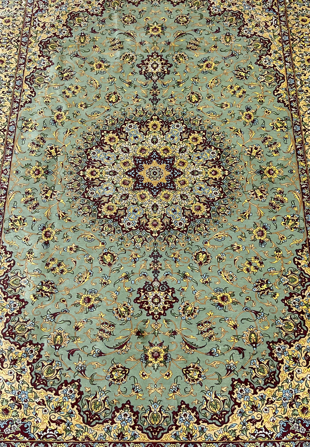 Midfield detail of a signed Mirmehdi Persian Qum silk rug highlighting intricate floral vines, sage green background, and fine silk knot density
